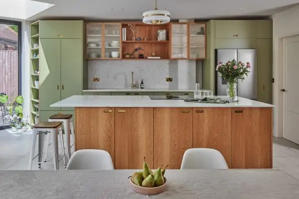 Chic family kitchen in Finchley with khaki green and London Plane cabinetry and extra texture added with fluted glass and brass details.