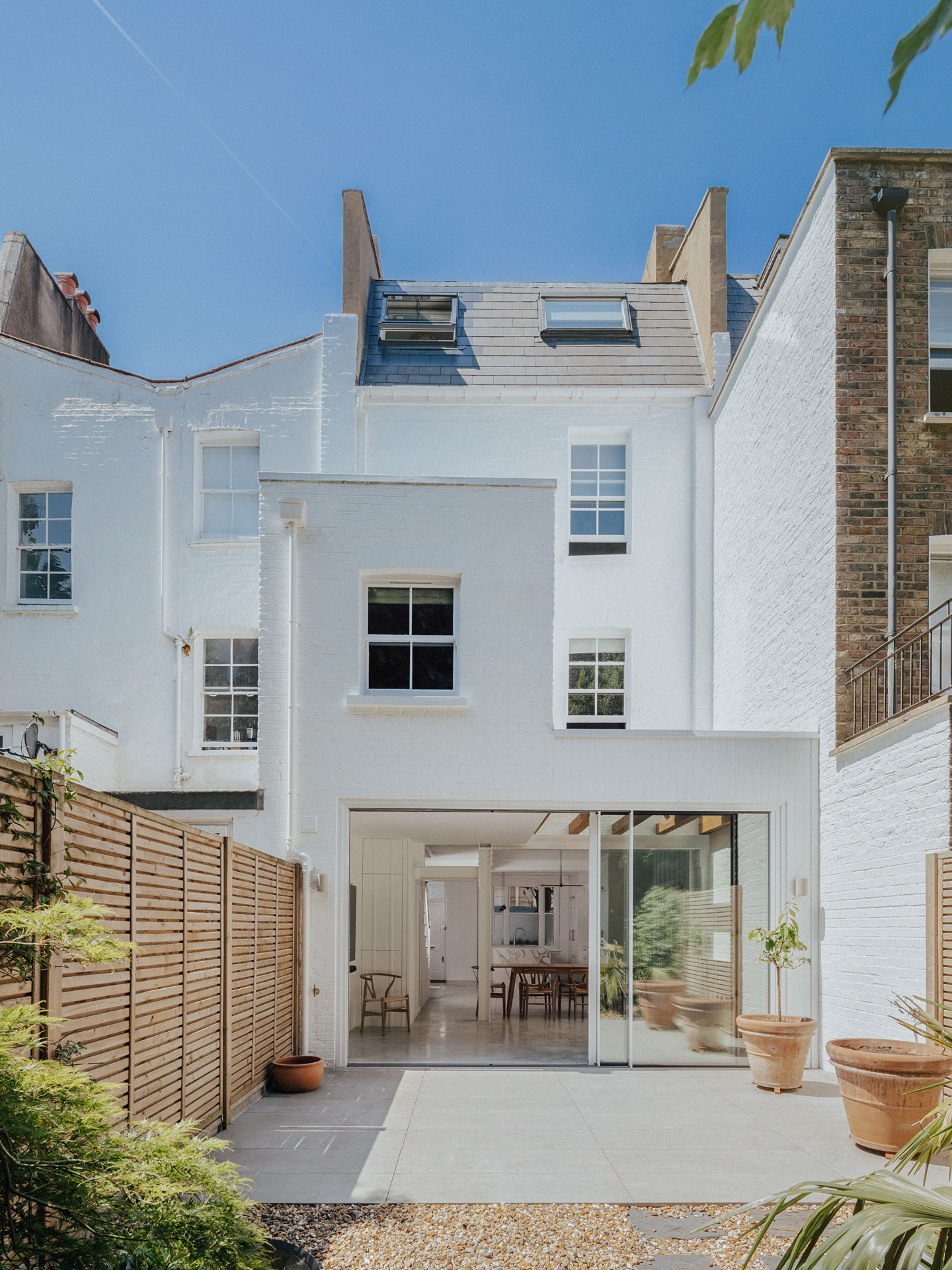 Sleek white minimalist Pluck kitchen with a swirling marble topped island in a renovated Notting Hill Victorian townhouse.