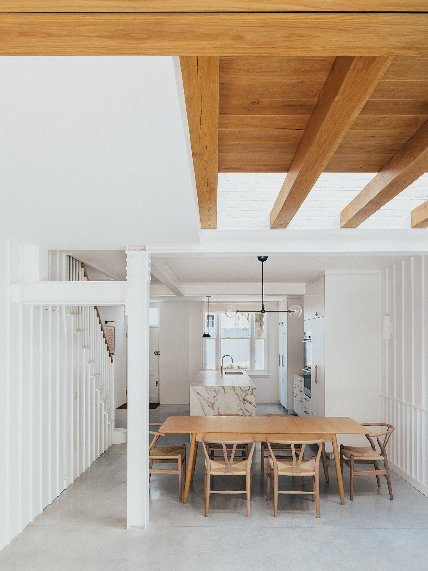 Neutral kitchen with white cabinetry, exposed oak beams and polished concrete flooring.