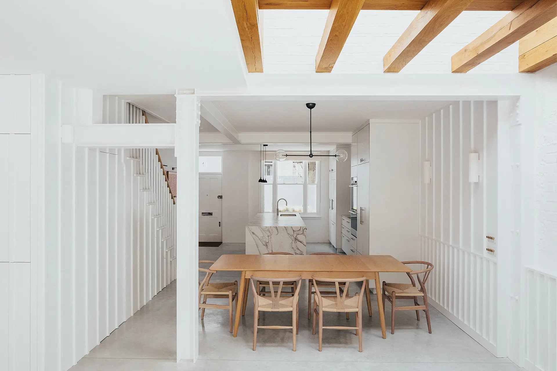 Sleek white minimalist Pluck kitchen with a swirling marble topped island in a renovated Notting Hill Victorian townhouse.
