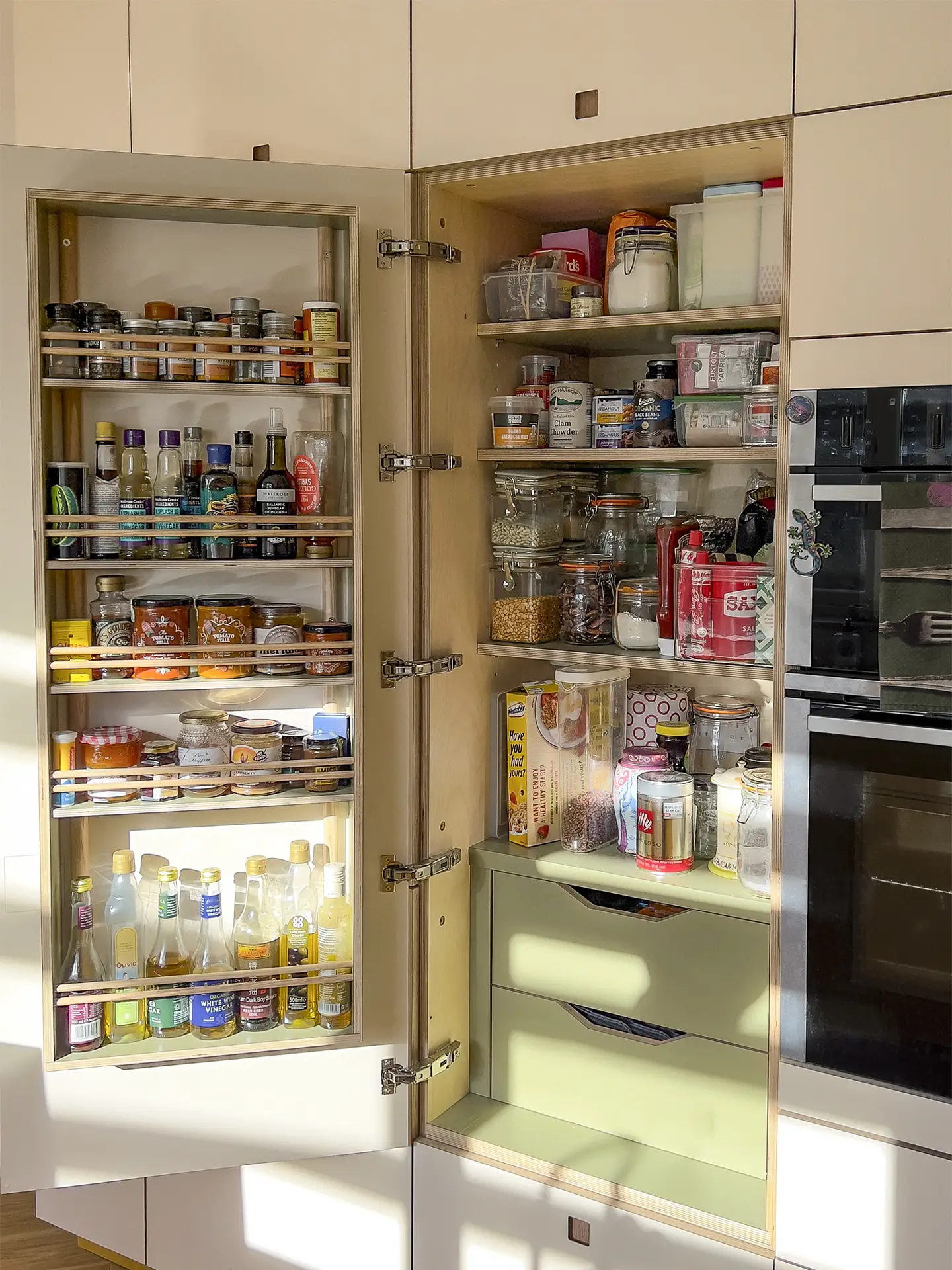 Larder in a small sunny yellow Pluck kitchen with a peninsula, shelving and glossy tile splashback.