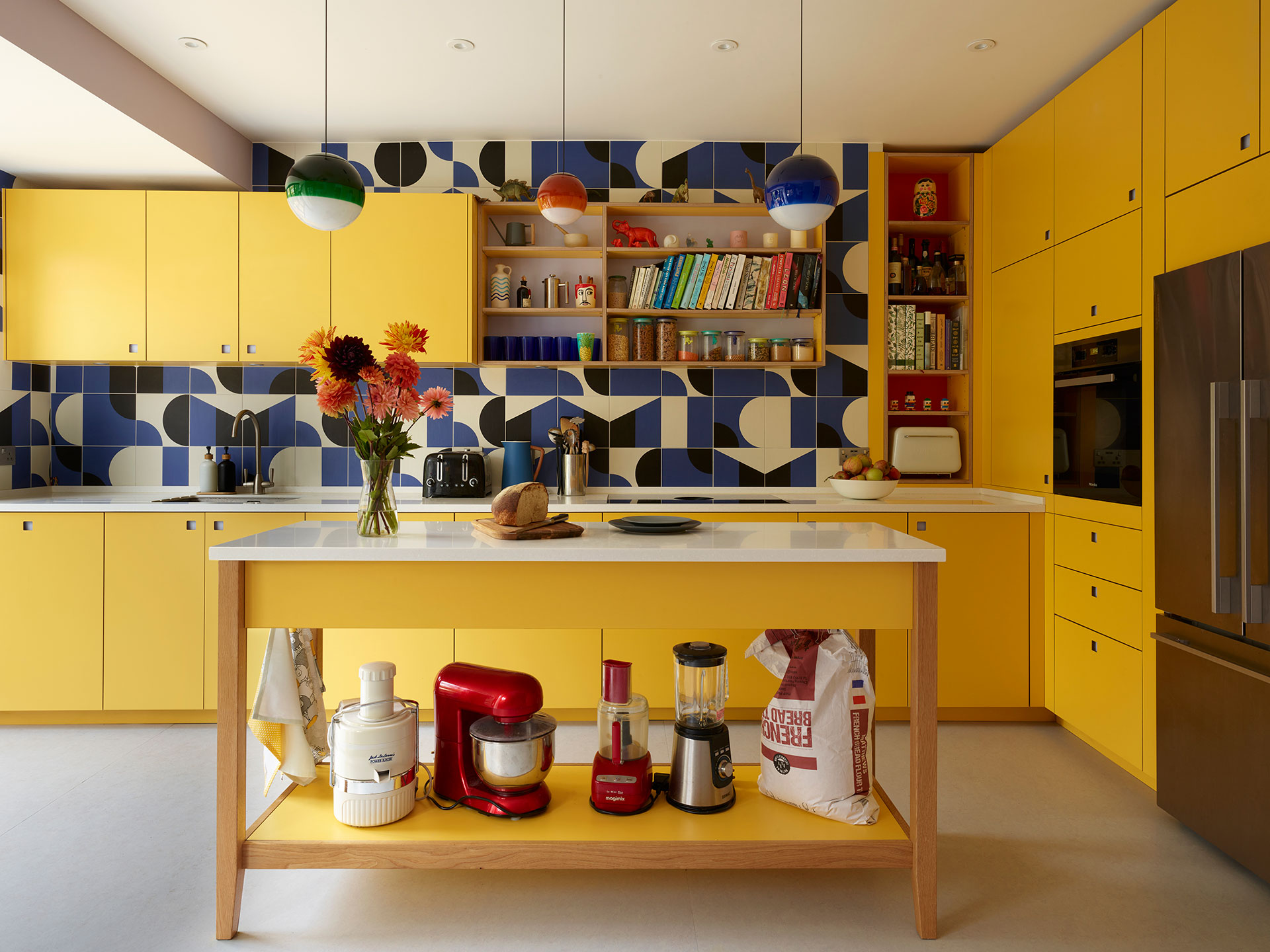 Bright sunshine yellow kitchen in Herne Hill with a freestanding prep table island and cobalt blue patterned tile splashback.