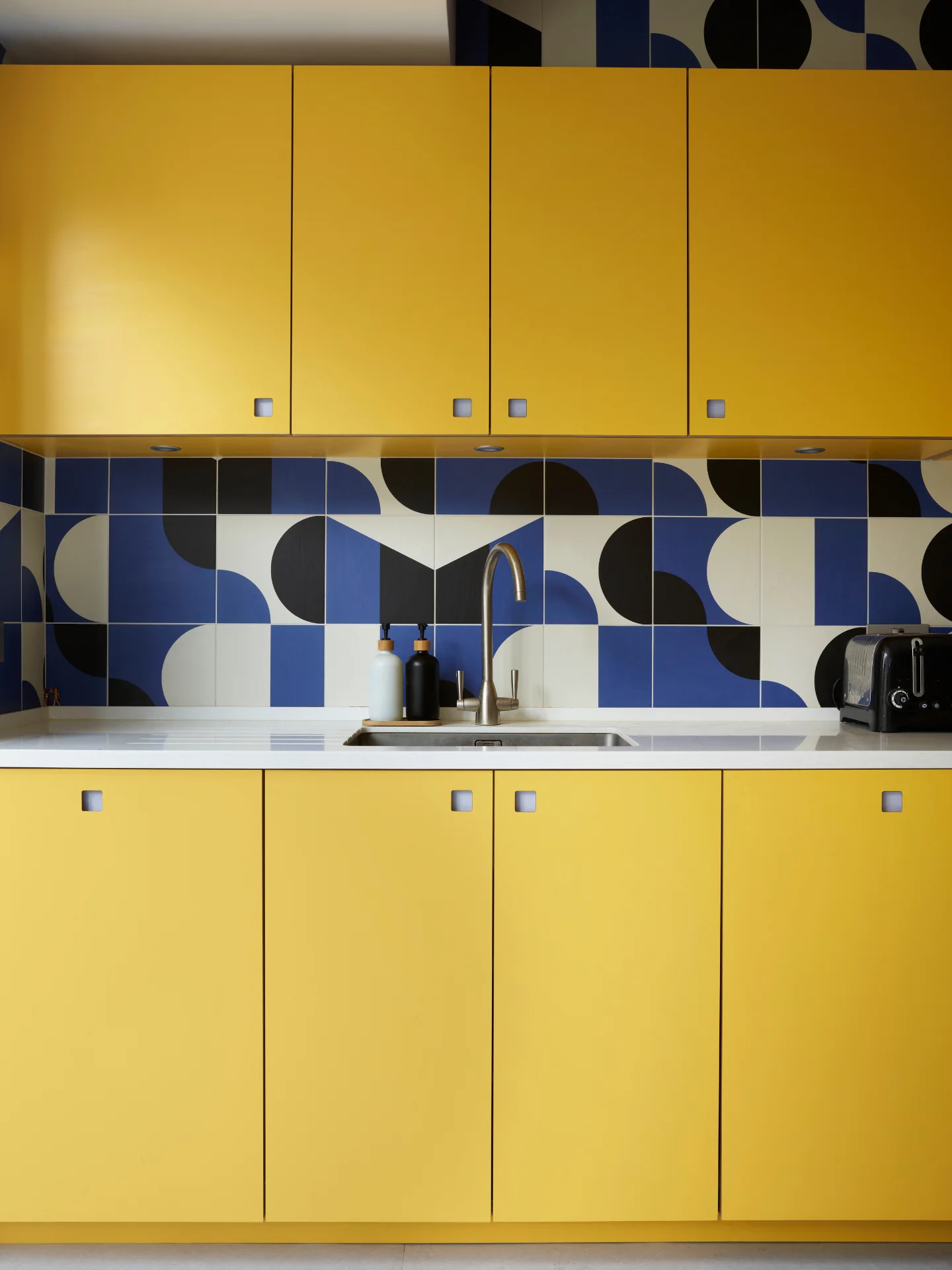 Bright sunshine yellow kitchen in Herne Hill with cobalt blue patterned tile splashback.