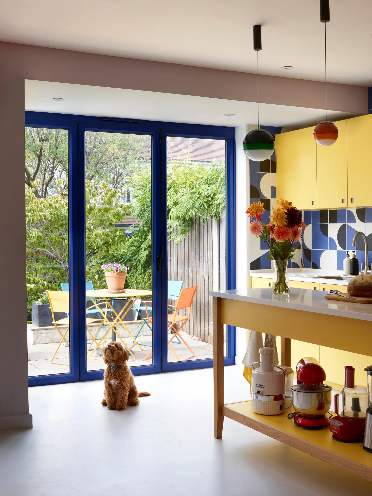 Bright sunshine yellow kitchen in Herne Hill with a freestanding prep table island and cobalt blue patterned tile splashback.