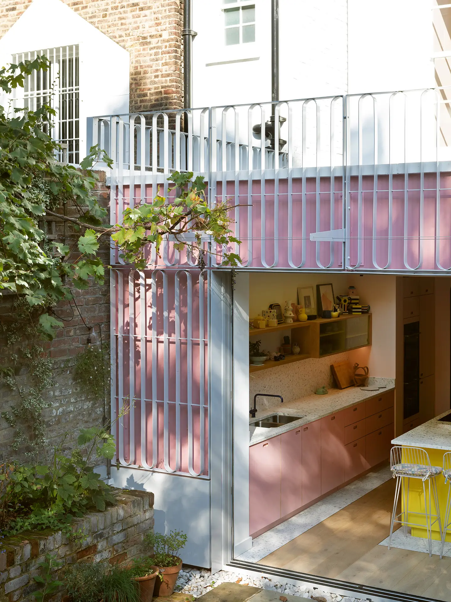 Colourful open plan Pluck kitchen with curves and a terrazzo topped island and floor tiles.