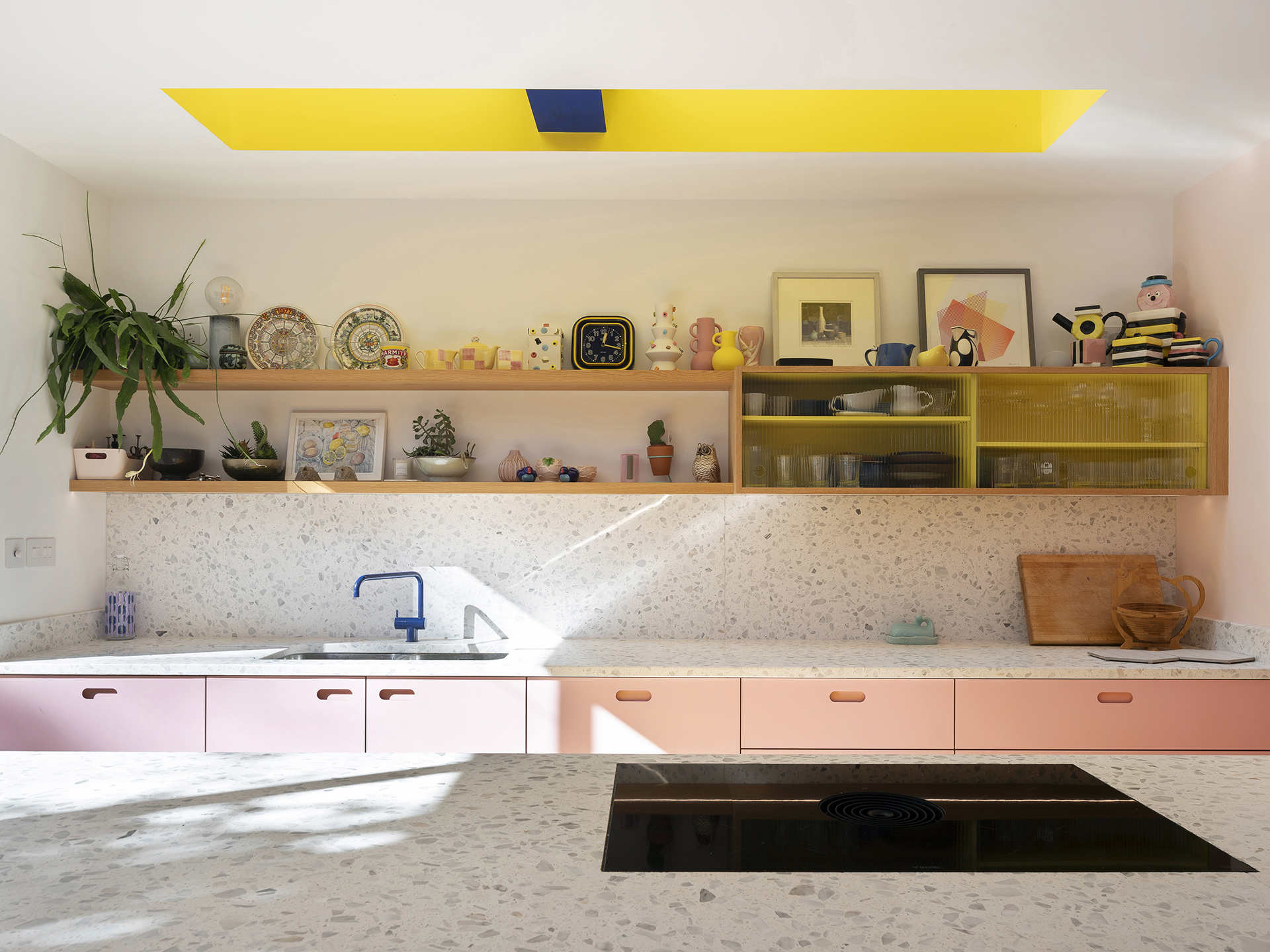 Colourful open plan Pluck kitchen with curves and a terrazzo topped island and floor tiles.