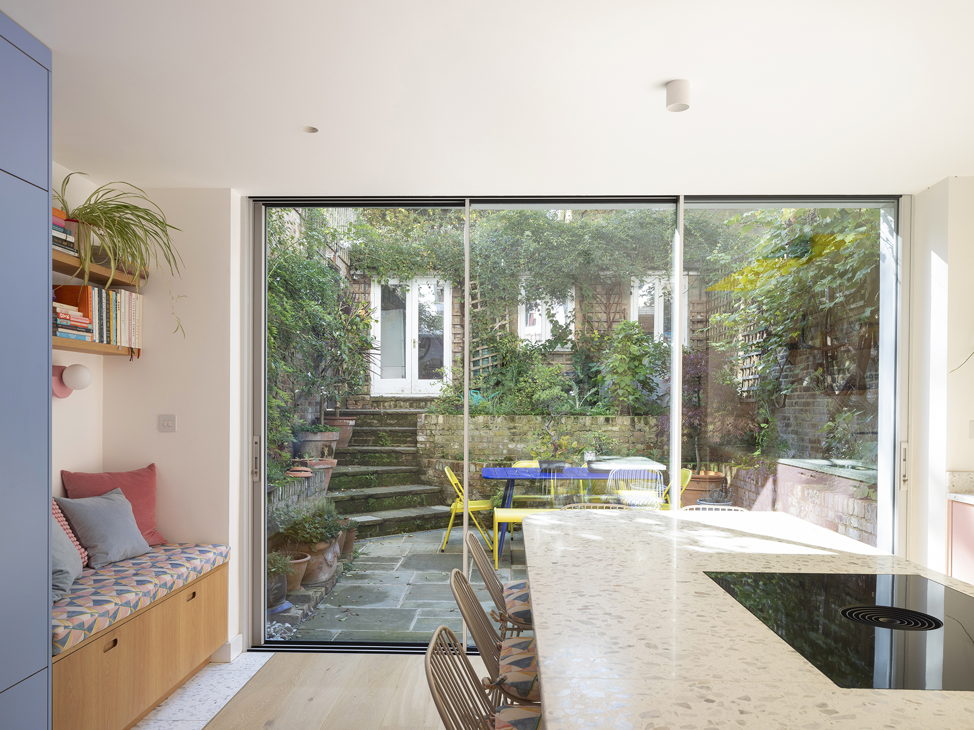 Colourful open plan Pluck kitchen with curves and a terrazzo topped island and floor tiles.