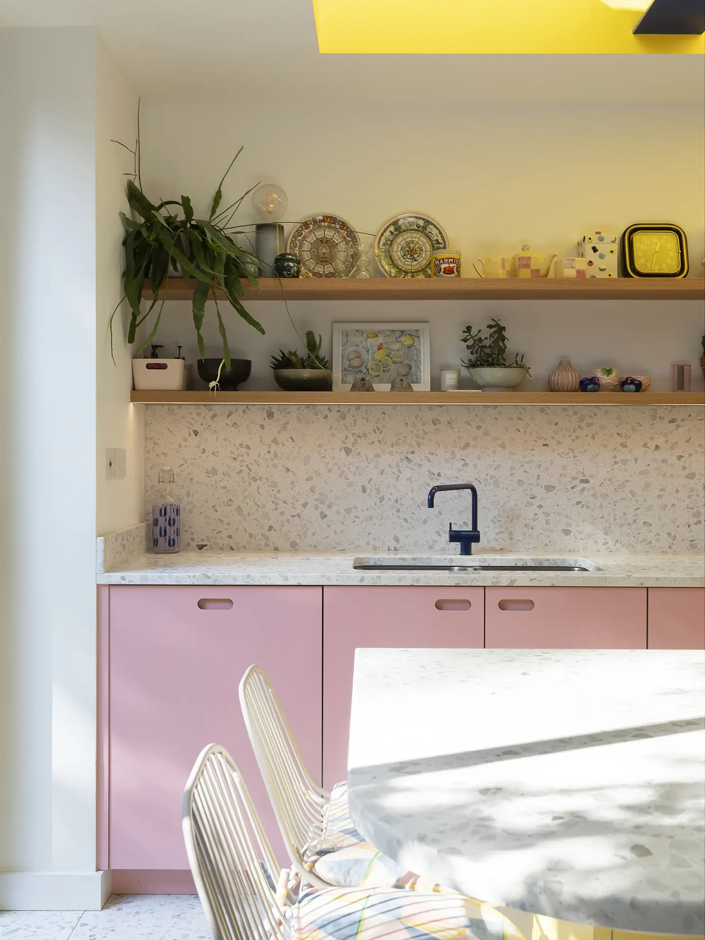 Colourful open plan Pluck kitchen with curves and a terrazzo topped island and floor tiles.