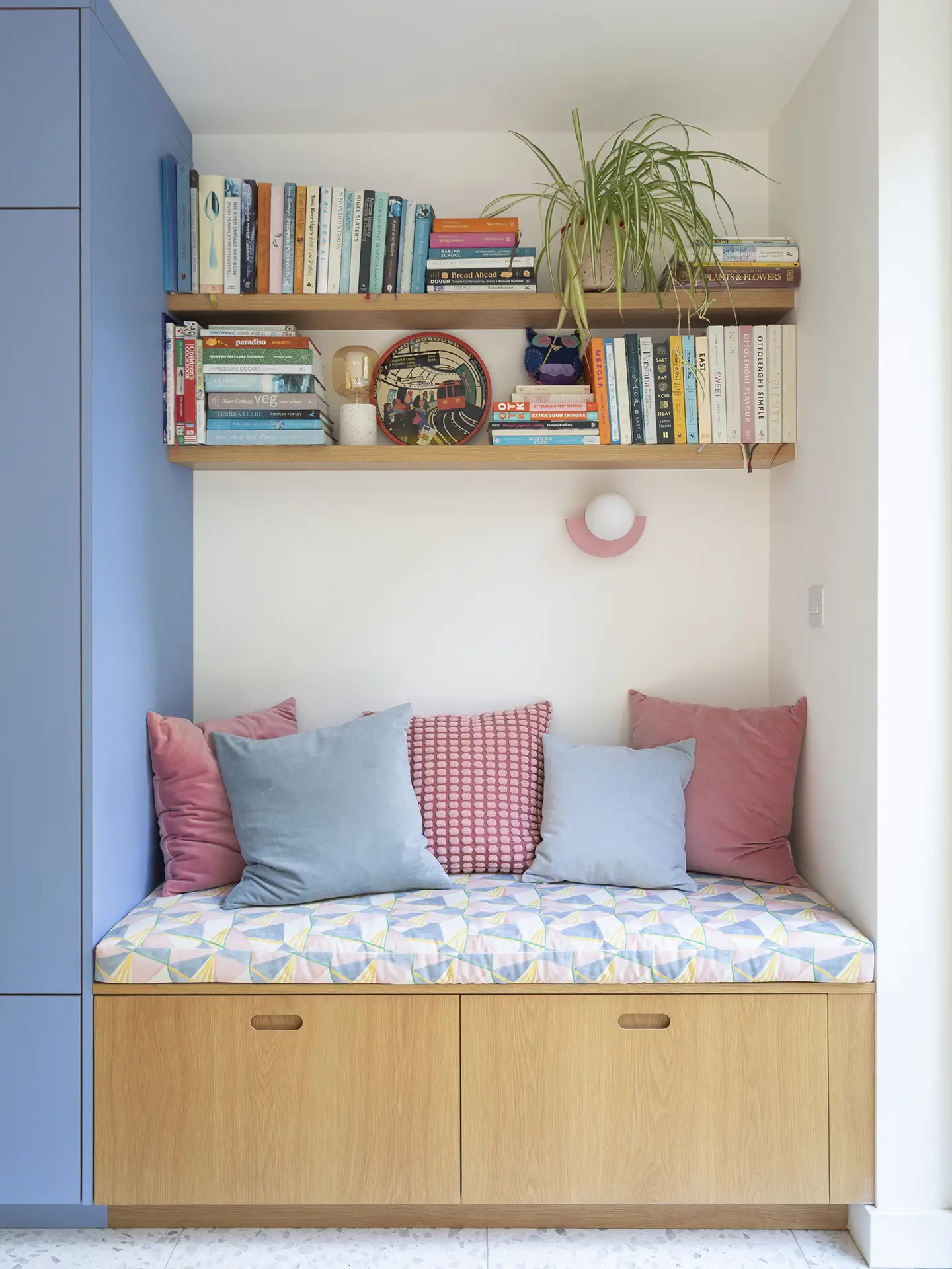 A bench seat in a colourful open plan Pluck kitchen with curves and a terrazzo topped island and floor tiles.