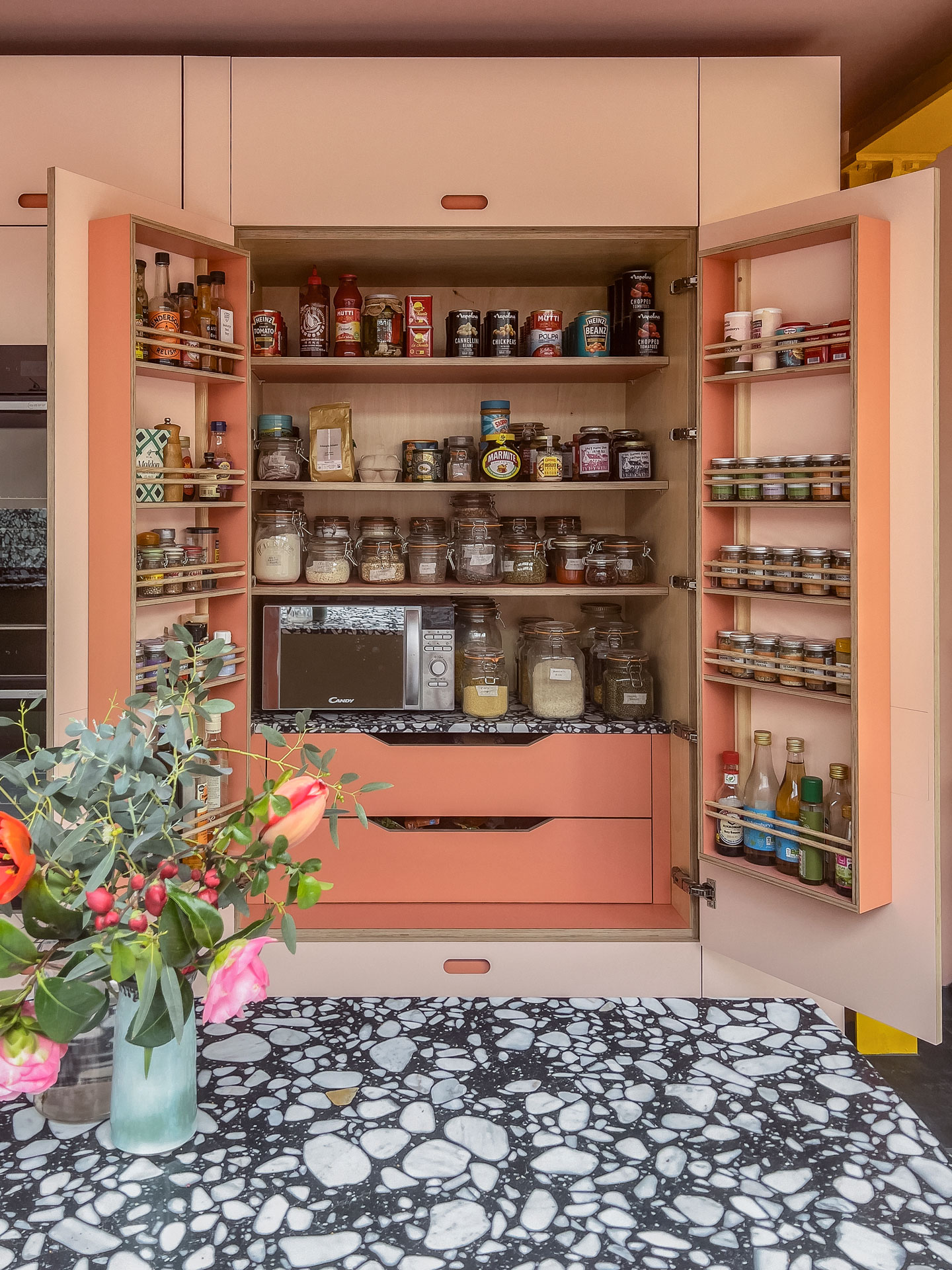 An organised open Pluck larder with two shades of pink and black and white terrazzo worktop.