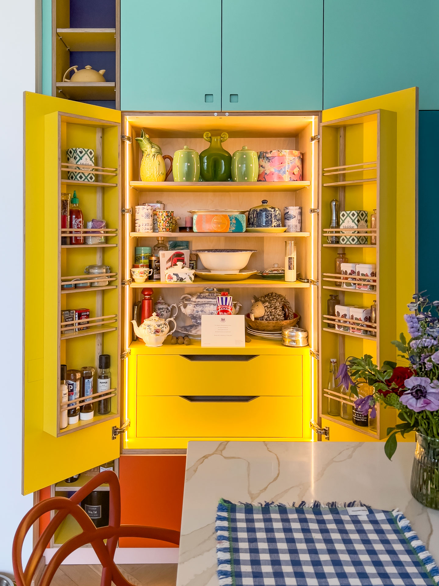 Open Pluck larder cupboard with blue cabinets, yellow interior and lighting.