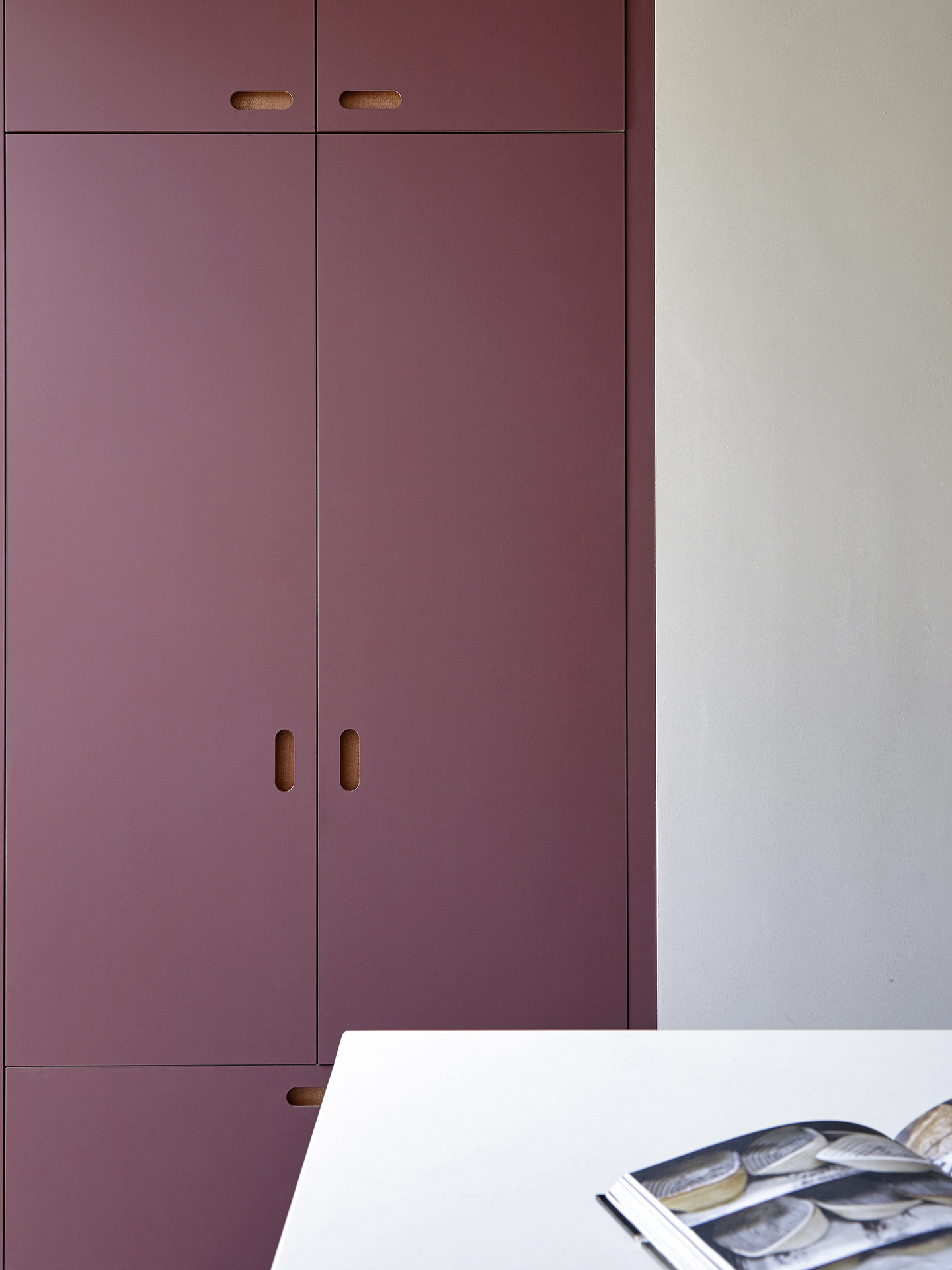 Soft, matt eco colours in a family kitchen including raspberry pink and oat coloured linen cupboards.