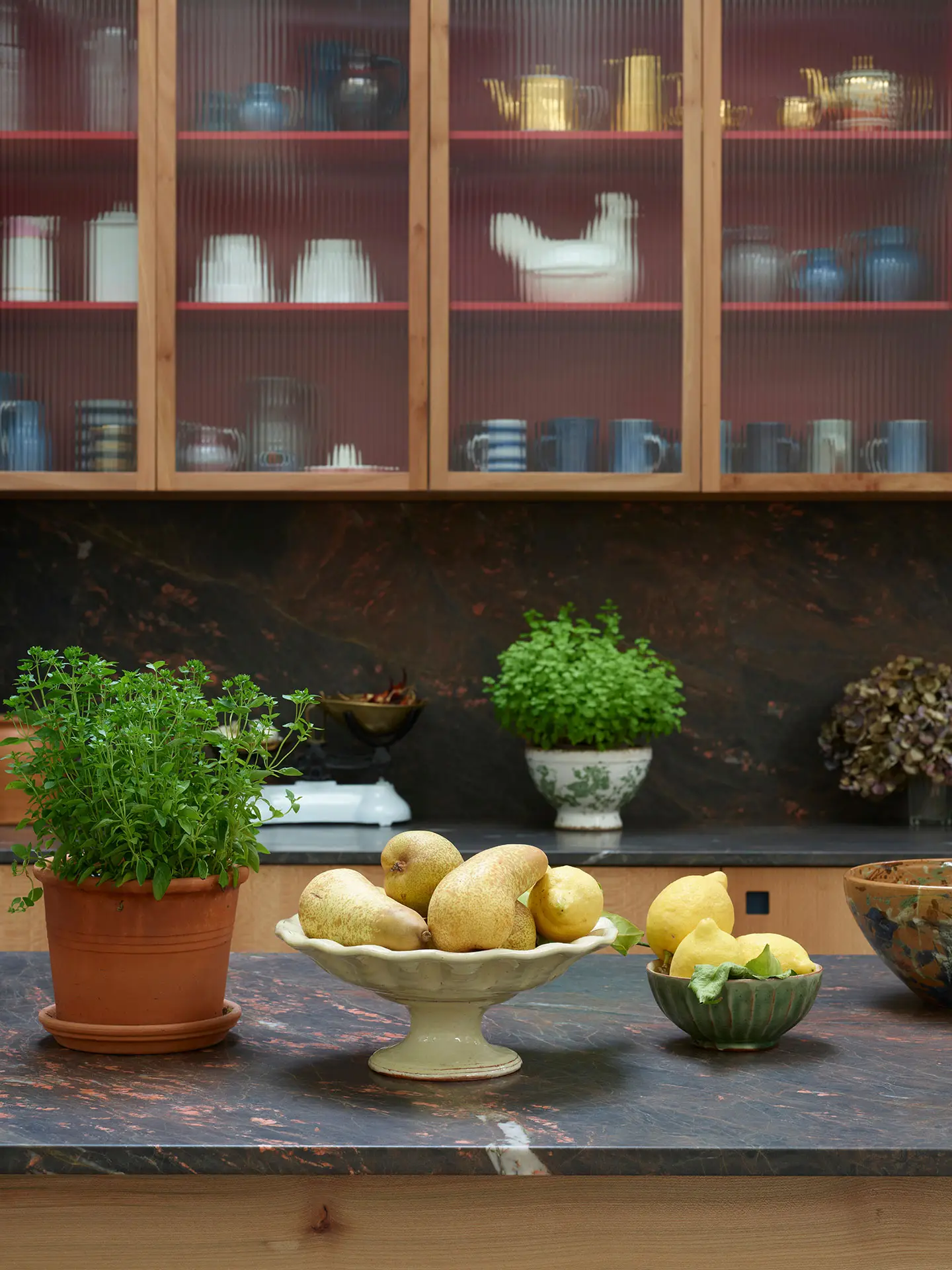 Kitchen showroom with London Plane, rich red and deep blue cupboards and a wooden work table with quartzite.