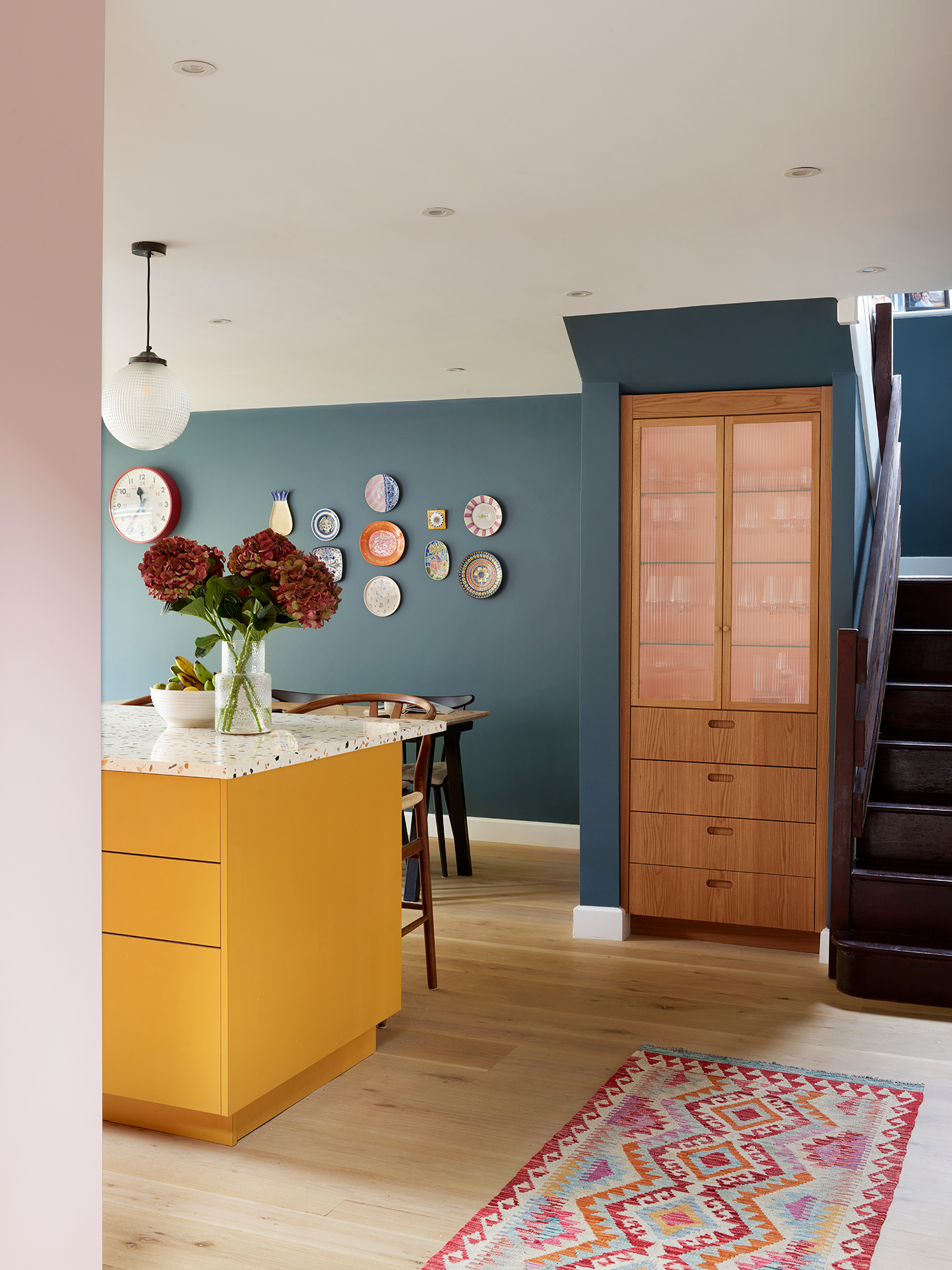 Open plan kitchen for a young family with colourful cabinets, a large island and blue walls.