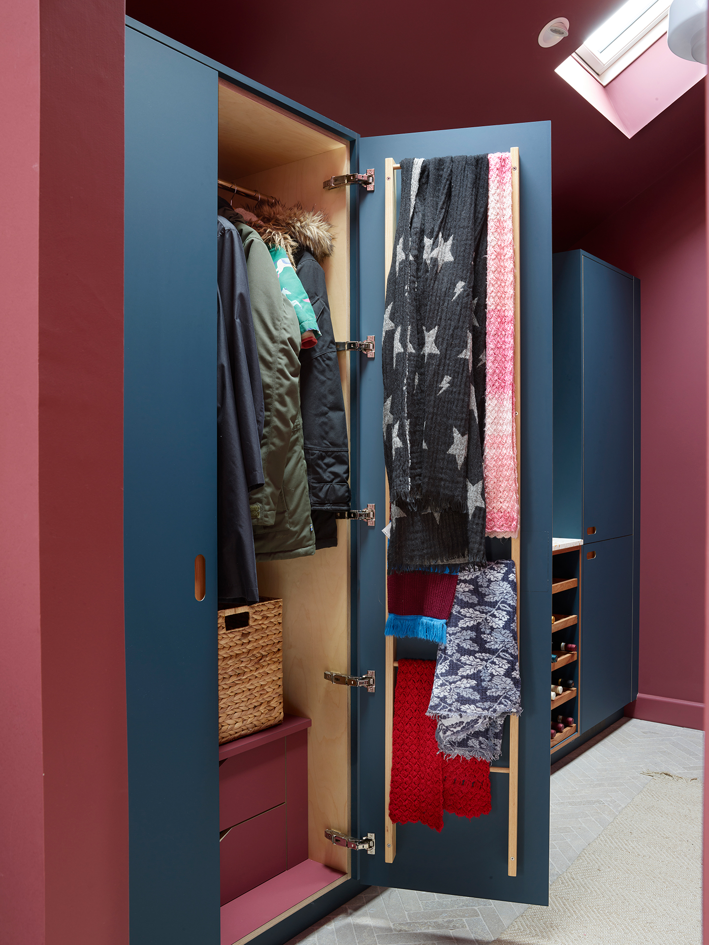 Cloak room with navy blue cabinetry and raspberry pink walls.