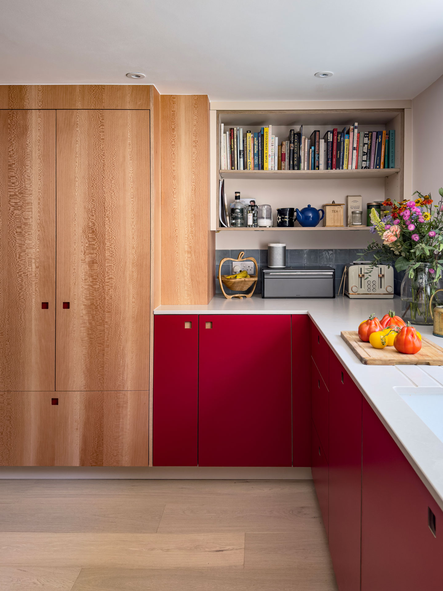 A basement kitchen in a London townhouse with bold Regent Red, London Plane wood and soft beige Eccles cabinetry.