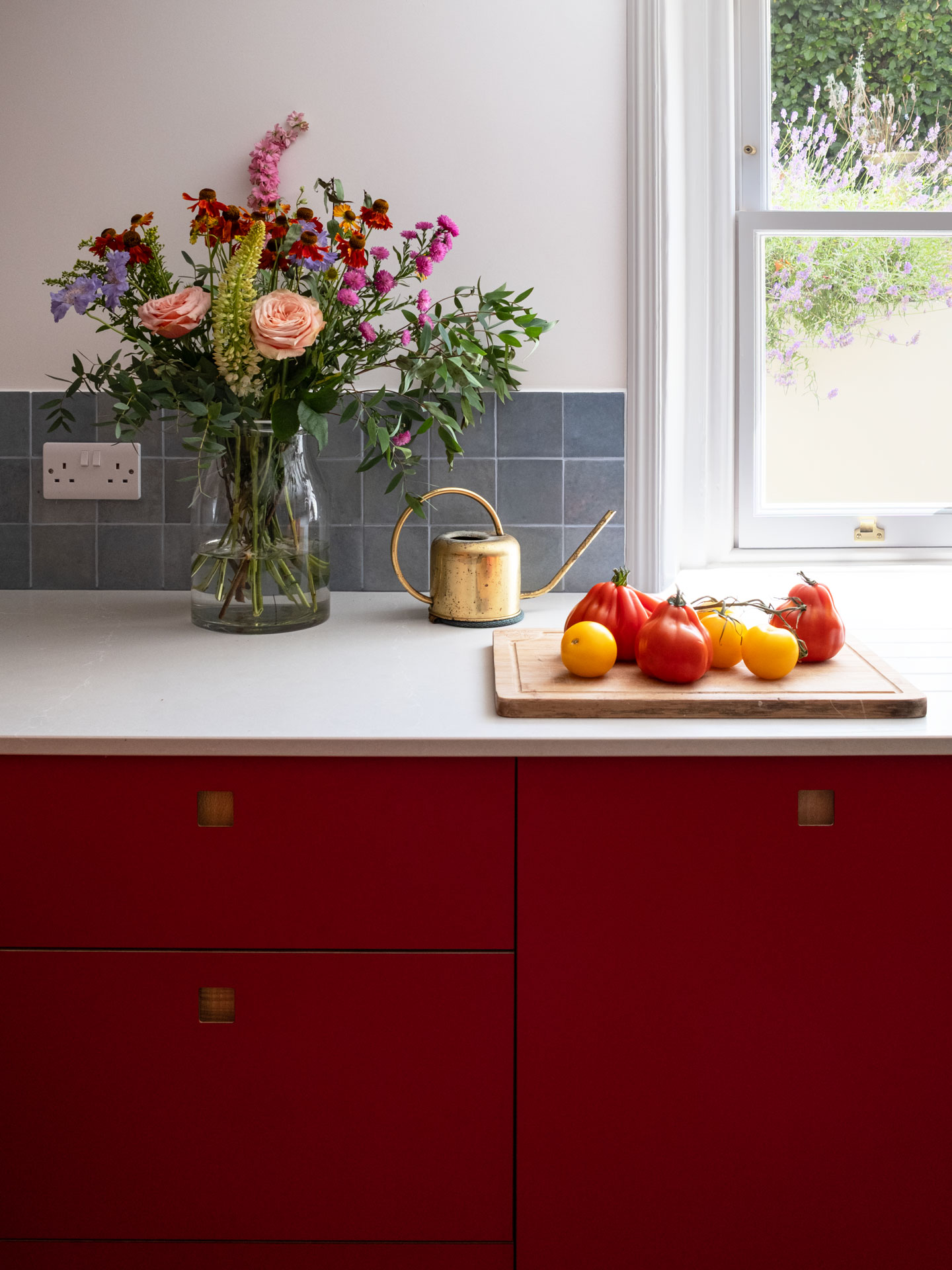 A basement kitchen in a London townhouse with bold Regent Red, London Plane wood and soft beige Eccles cabinetry.