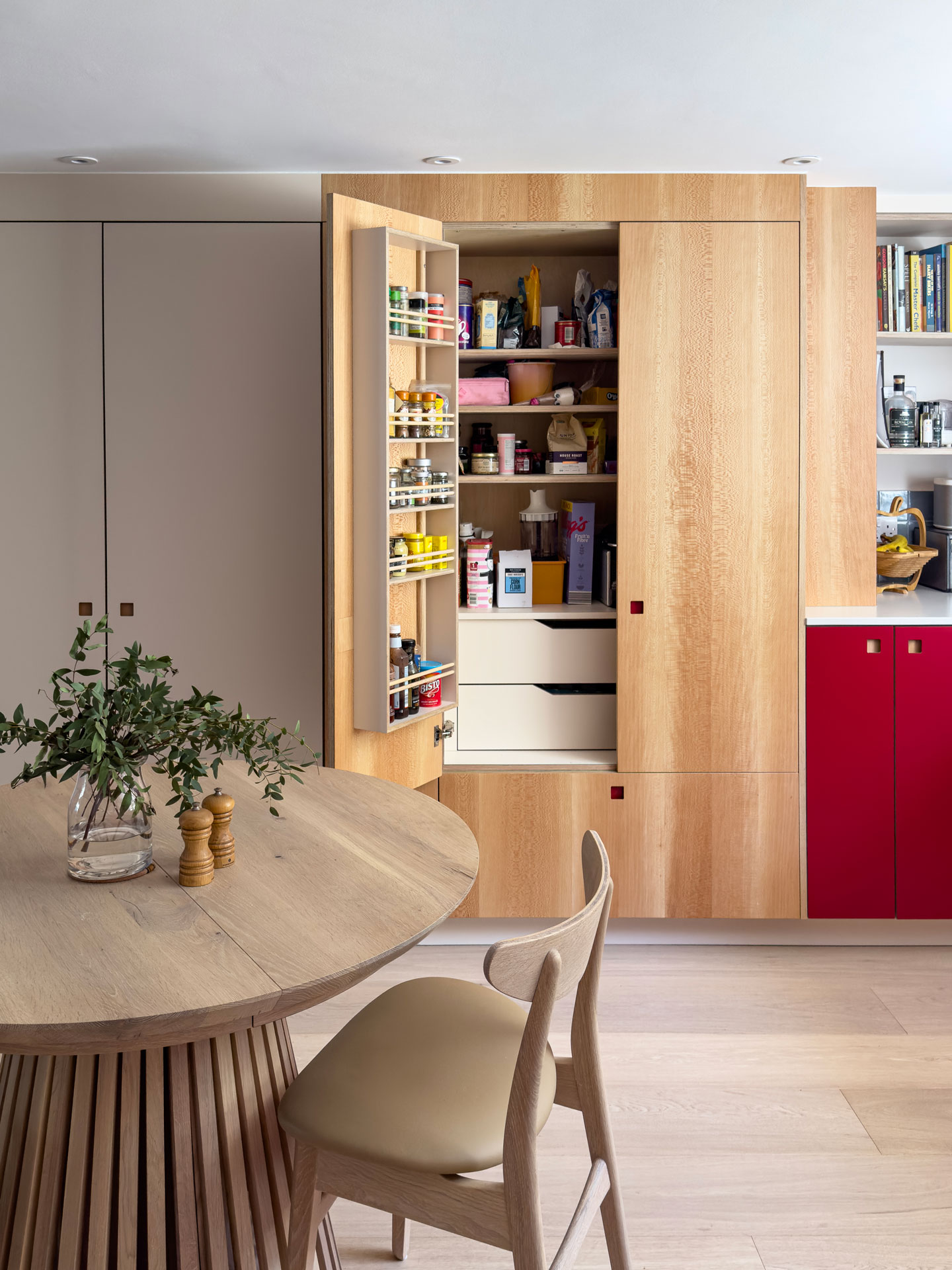 A u-shaped family kitchen in London with Pluck's Regent Red, London Plane wood and Eccles cabinets and a range cooker.