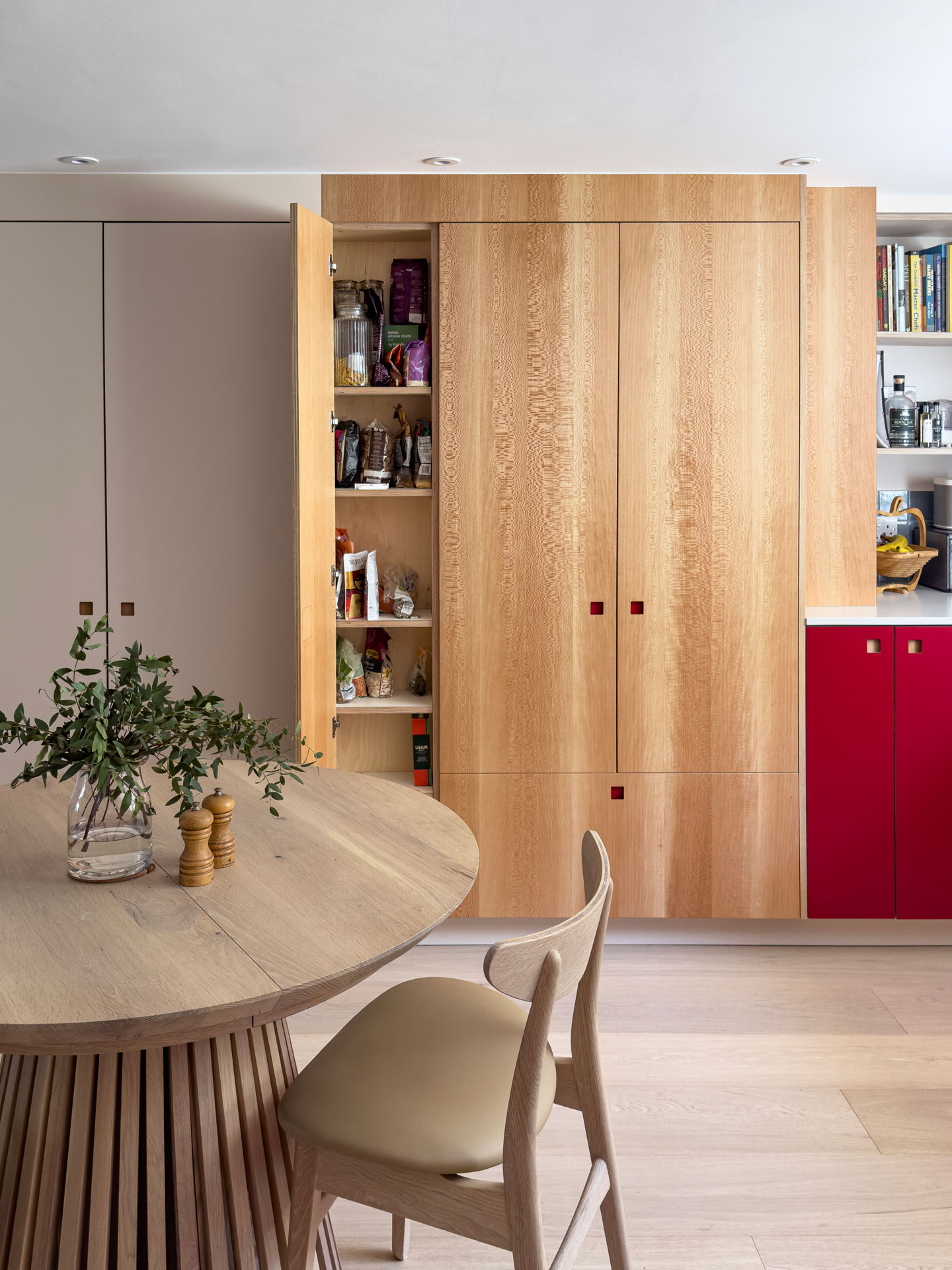 A basement kitchen in a London townhouse with bold Regent Red, London Plane wood and soft beige Eccles cabinetry.
