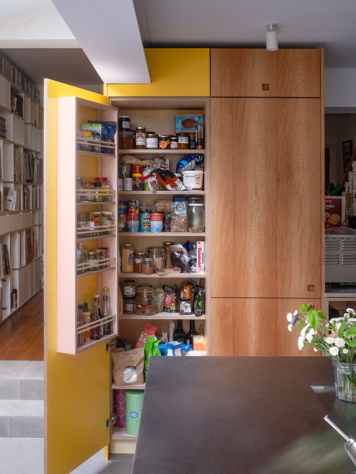 A busy family kitchen with an island, dining table, keyboard, soft seating and garden views.