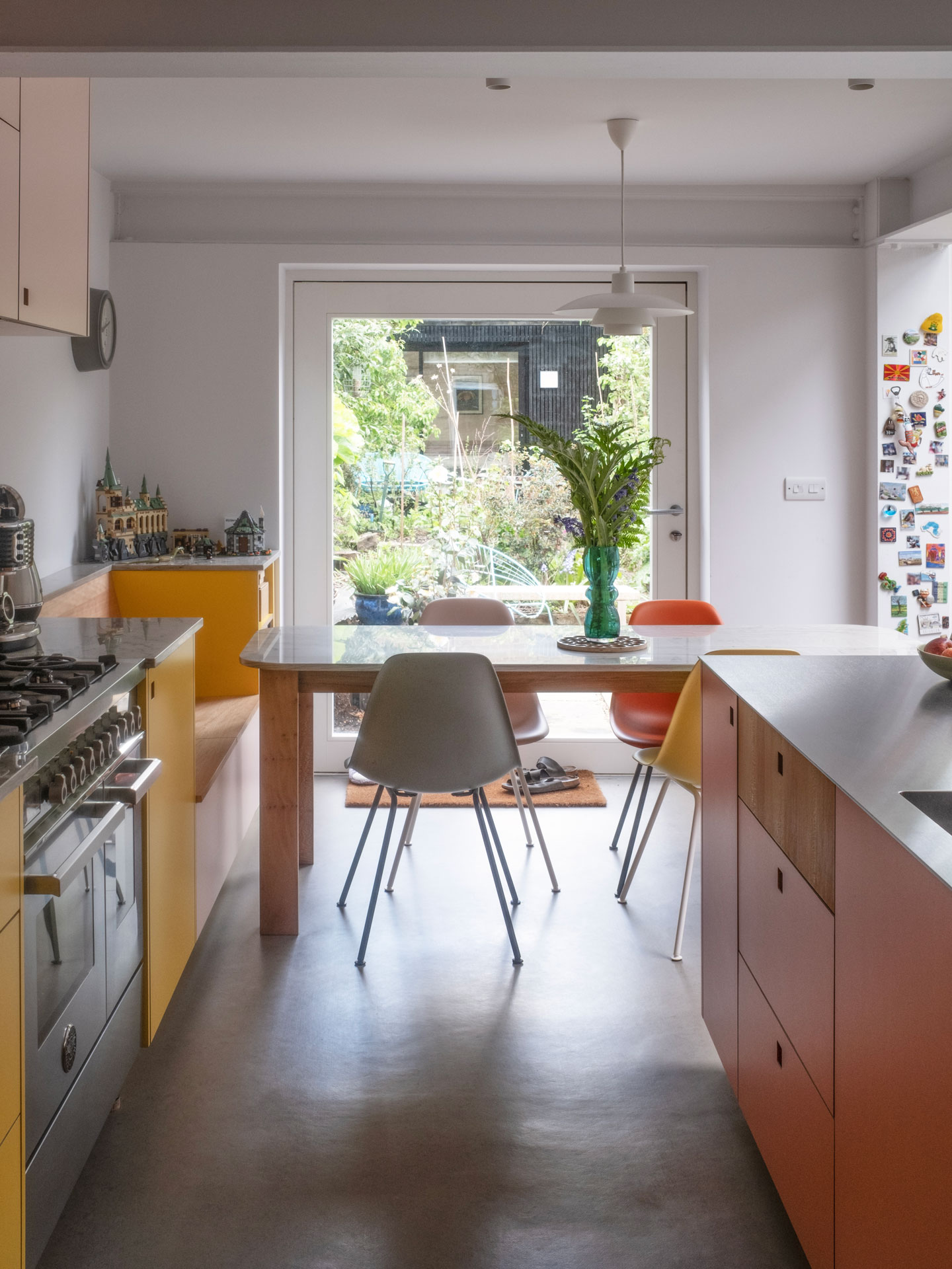 A busy family kitchen with an island, dining table, keyboard, soft seating and garden views.