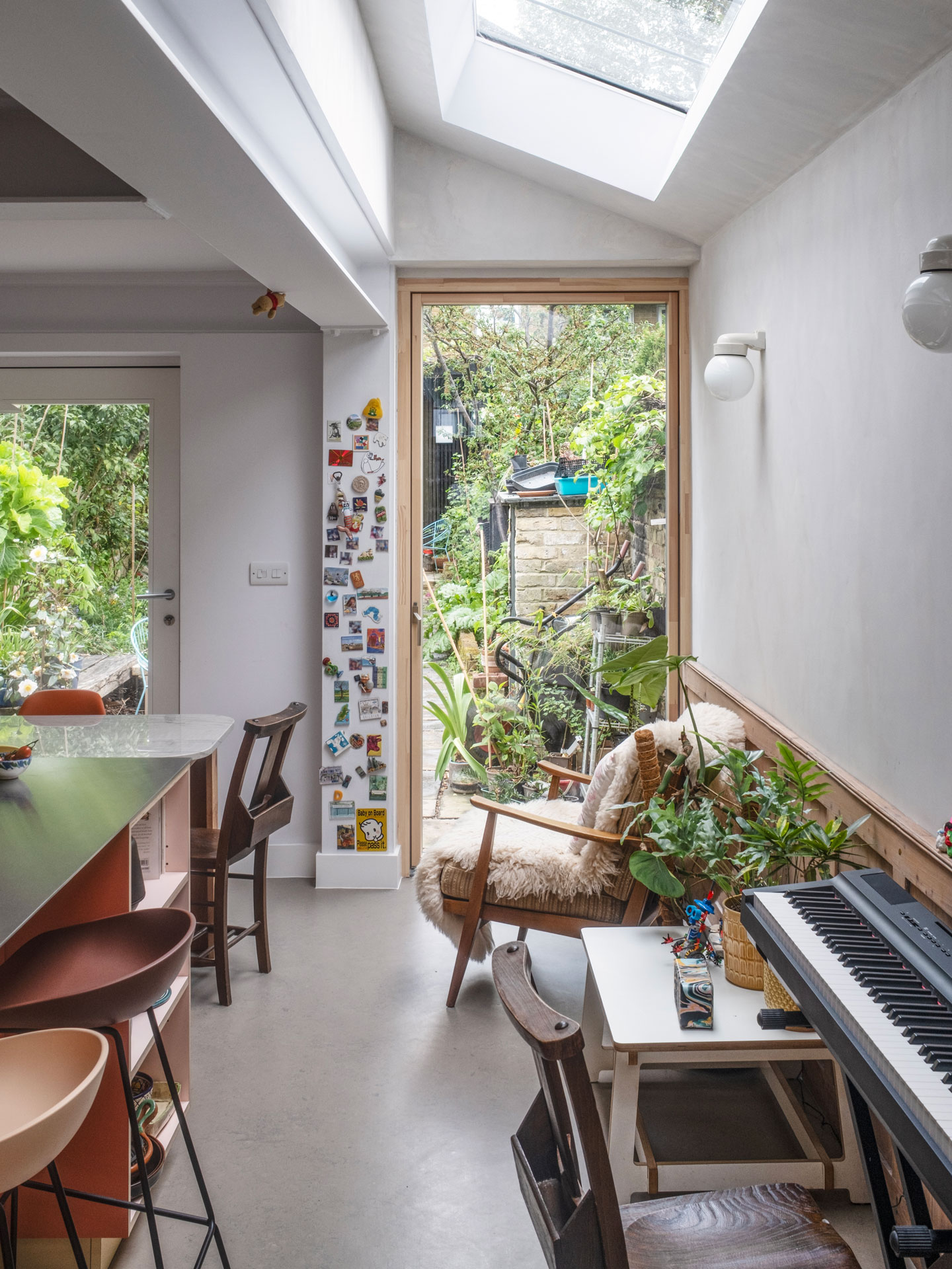 A busy family kitchen with an island, dining table, keyboard, soft seating and garden views.