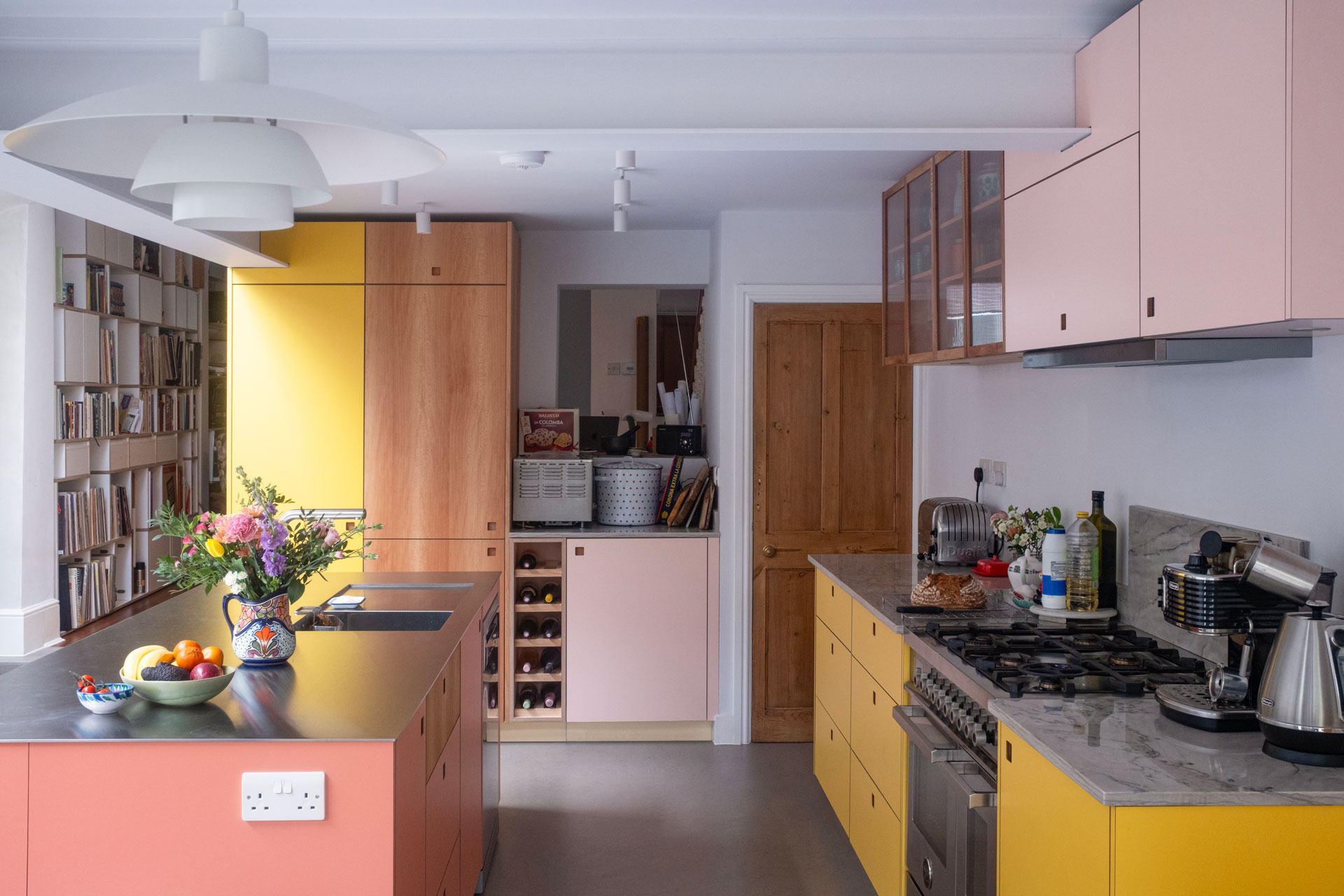 A busy family kitchen with an island, dining table, keyboard, soft seating and garden views.