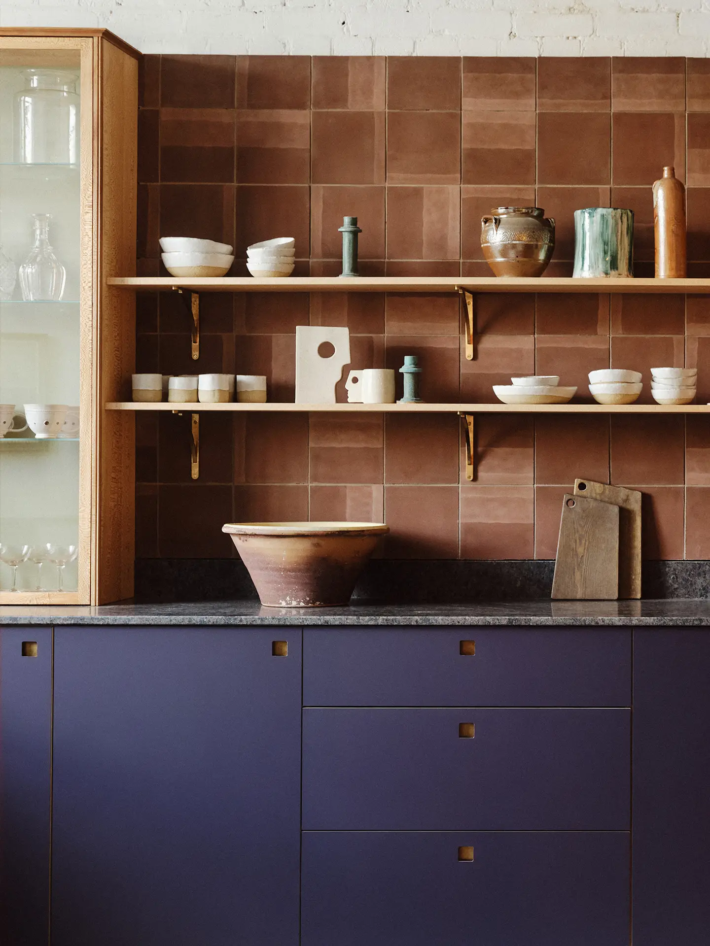 A Pluck kitchen in an East London showroom with Aubergine purple, London Plane wood and mustard yellow cabinetry.
