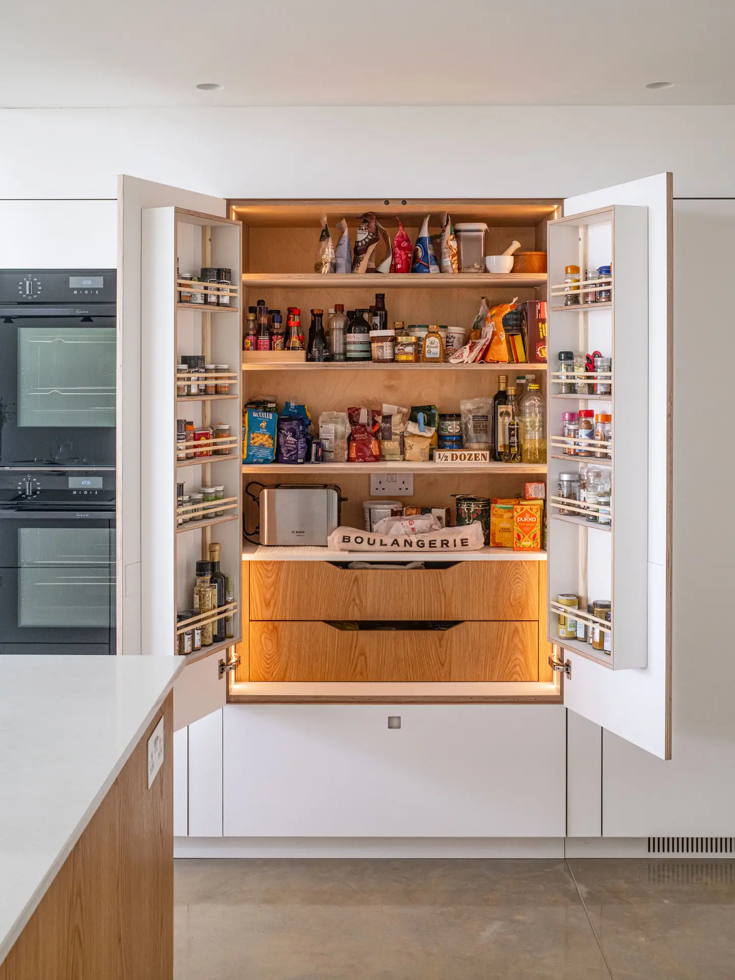 White and Oak wood custom cabinetry in a Pluck kitchen with an island and larder in Cheltenham.