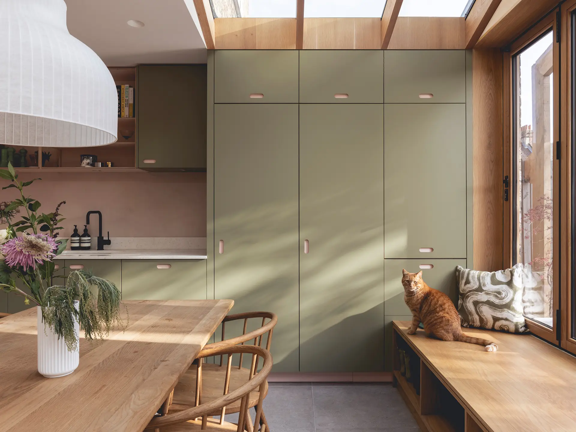 Pluck-A-Nature-Inspired-Kitchen-in-Hither-Green-19 Pink and green open plan Pluck kitchen including an island and plaster walls.