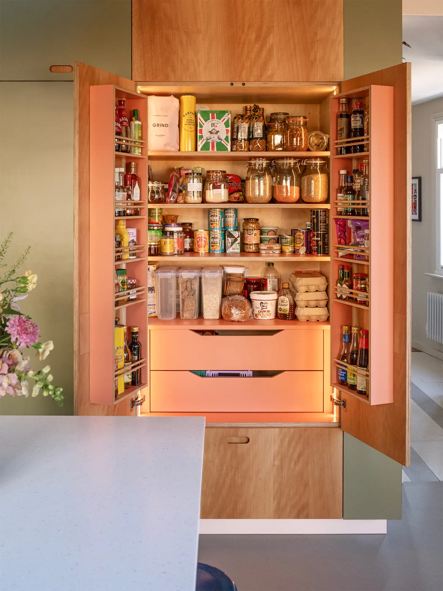Kitchen larder cupboard with internal lights, shelving and a microwave that sits on drawers.