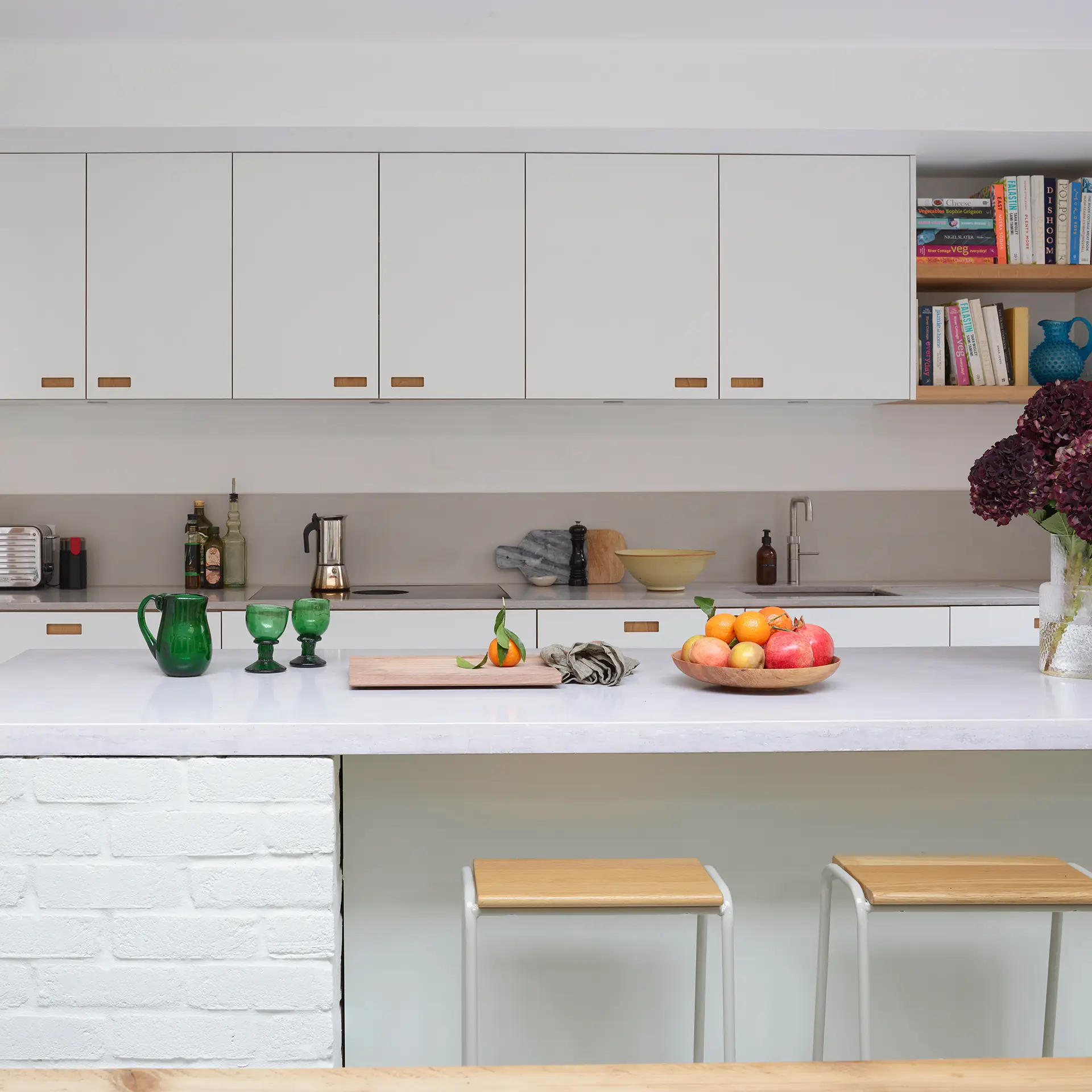 Minimalist Pluck kitchen with white cabinetry and concrete worktops.