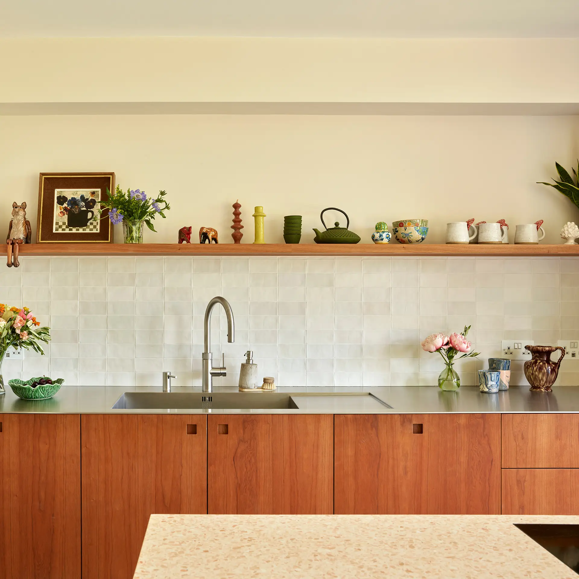A minimalist Kitchen with stainless steel worktops, a single wooden shelf on the wall and Cherry cabinetry.