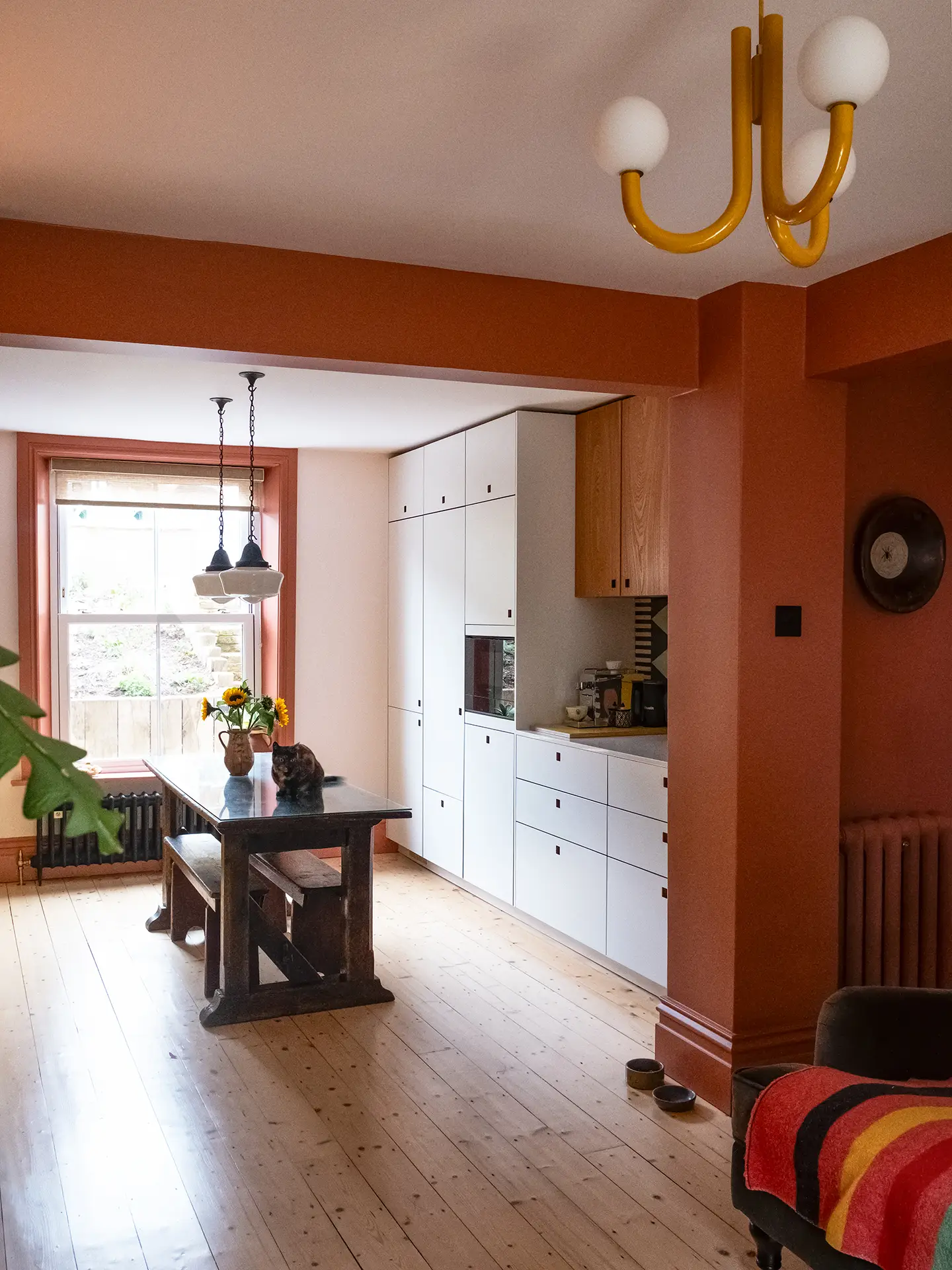 A galley kitchen in a London family home with white, wood, and yellow Pluck cabinetry and colourful tiles.