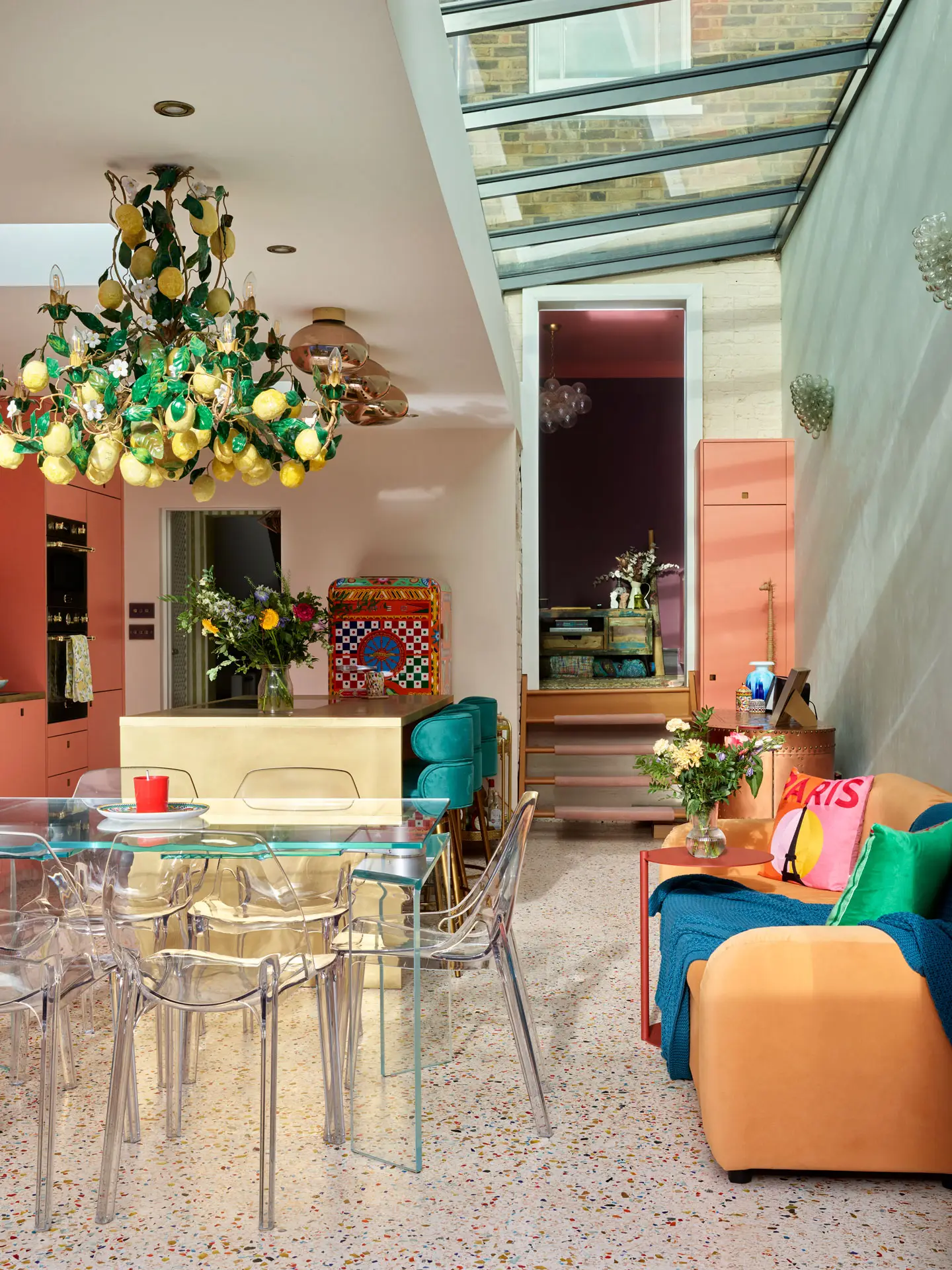 A coral pink Pluck kitchen with colourful terrazzo flooring, brass worktops and an Italian lemon chandelier.