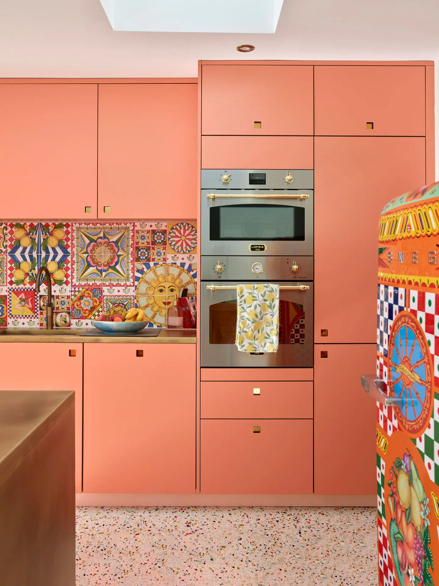 Coral pink Ritzy Pluck cabinetry in a glamorous Pluck kitchen including an island and larder.