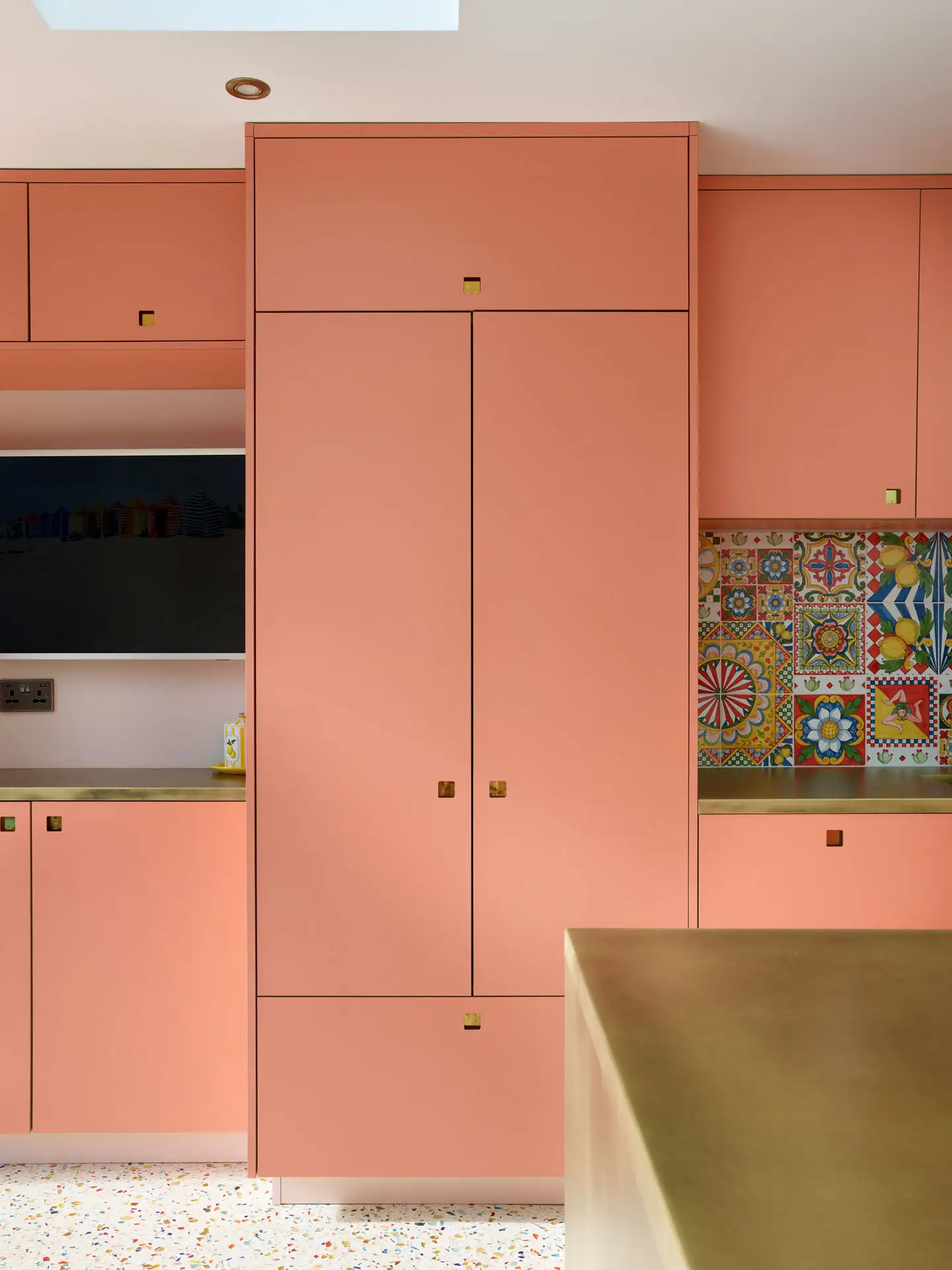 Coral pink Ritzy Pluck cabinetry in a glamorous Pluck kitchen including an island and larder.