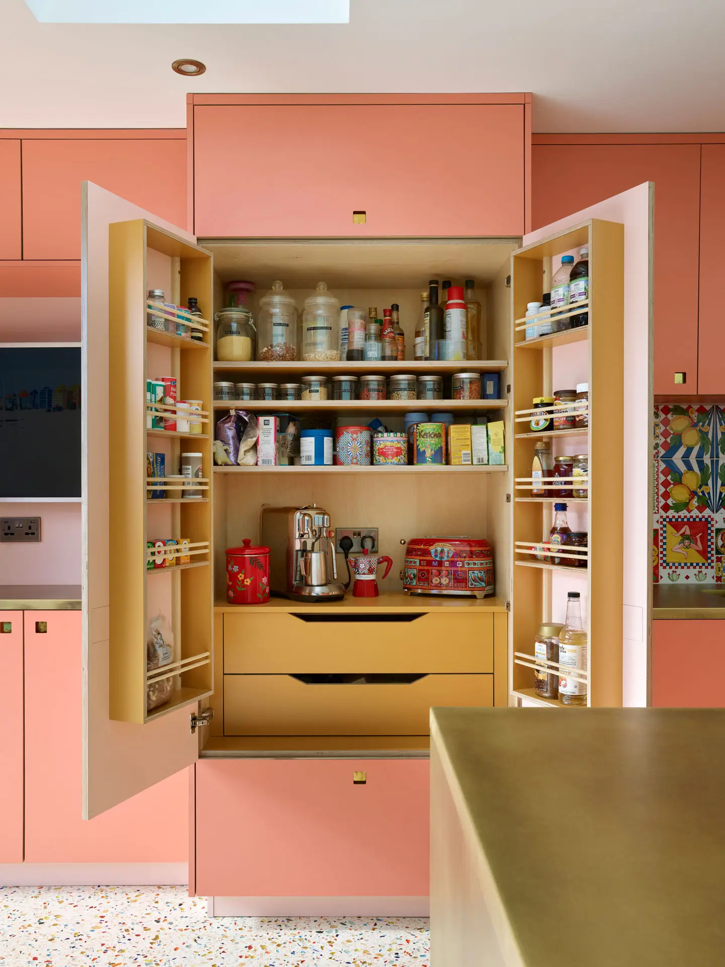 Coral pink Ritzy Pluck cabinetry in a glamorous Pluck kitchen including an island and larder.