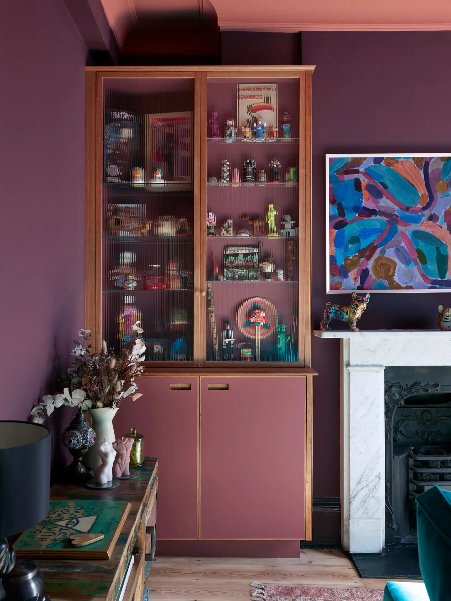 Raspberry and London Plane glass cabinets in a snug, alongside a coral pink Pluck kitchen.