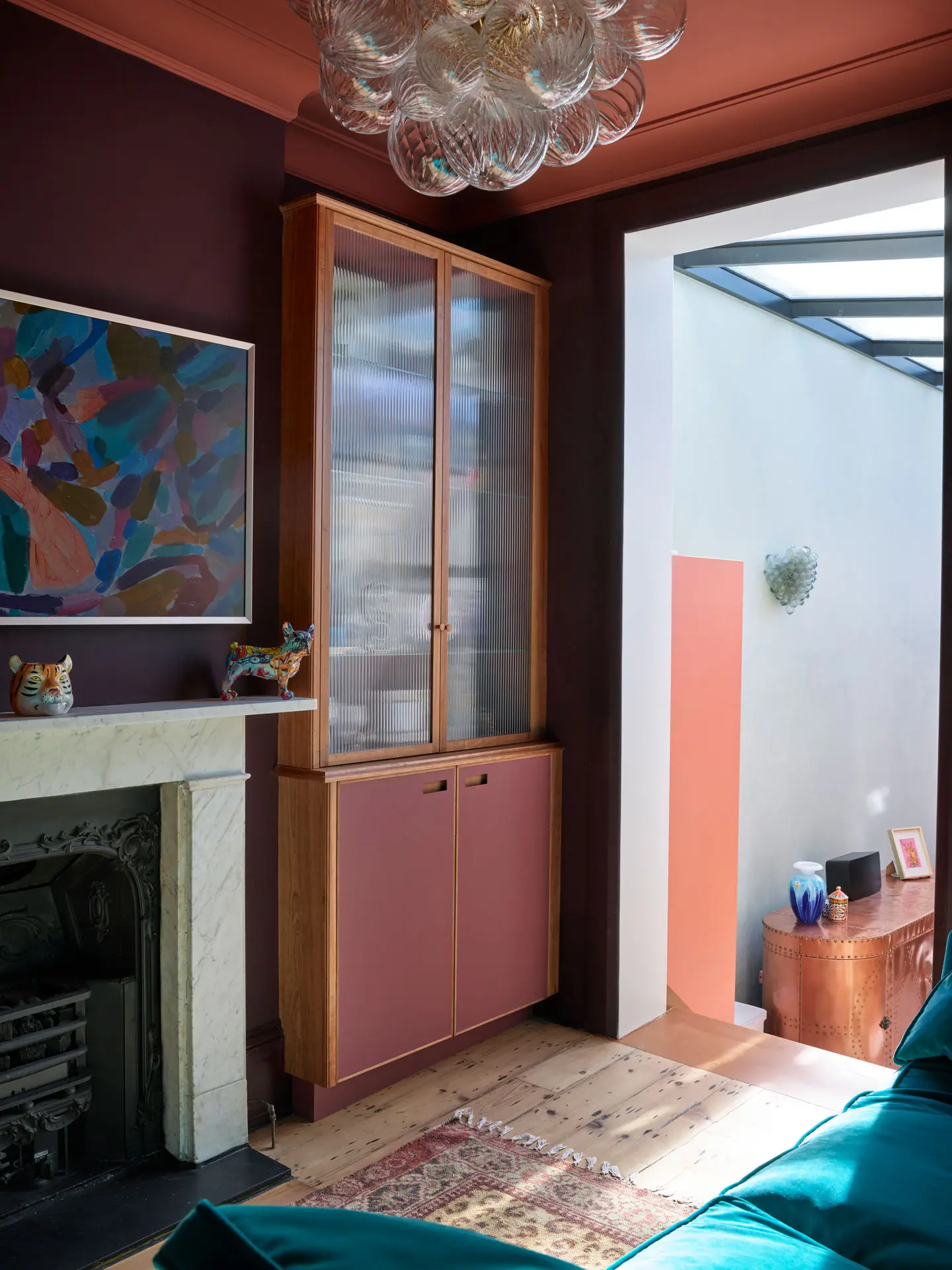 Raspberry and London Plane glass cabinets in a snug, alongside a coral pink Pluck kitchen.
