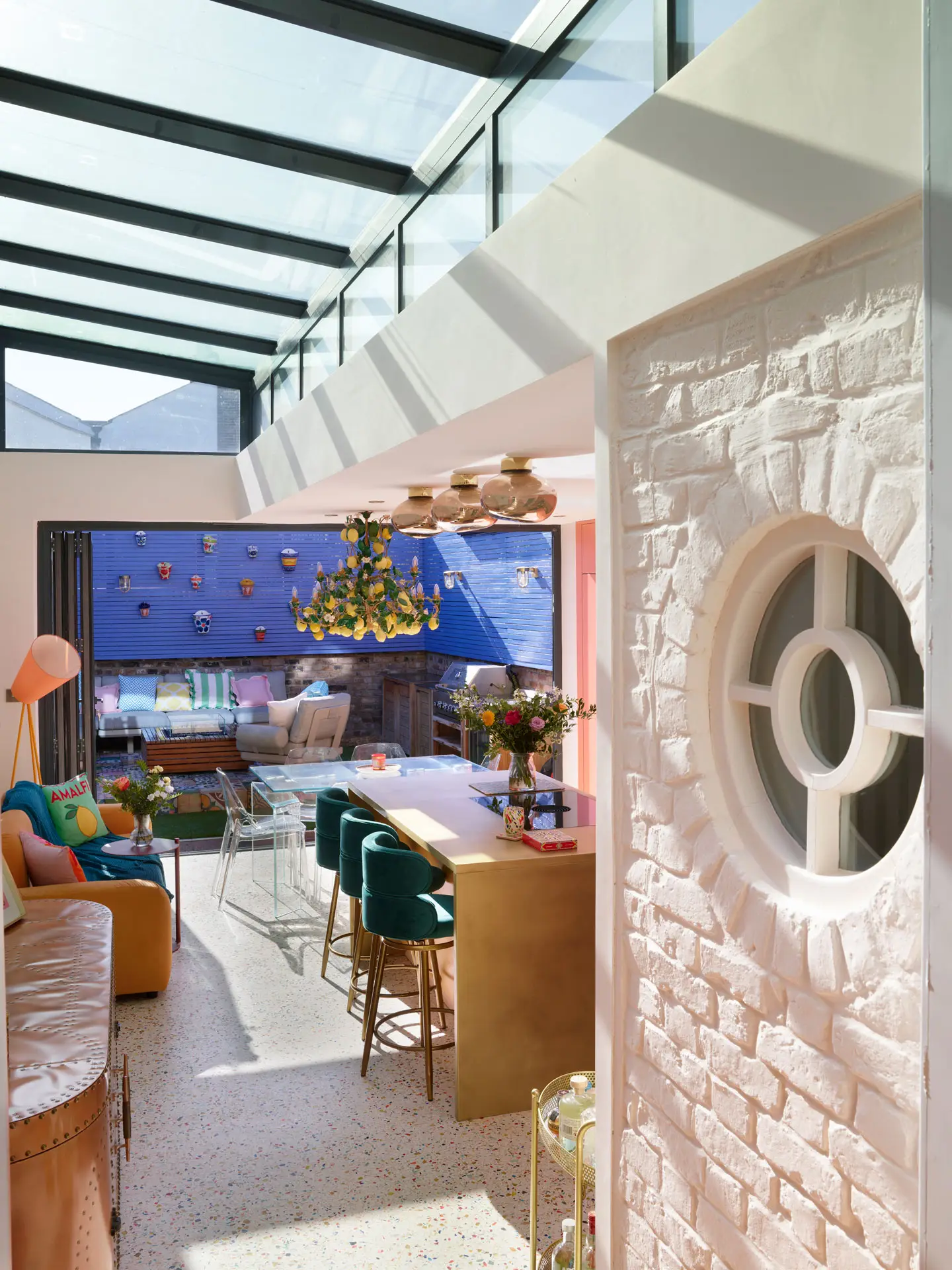 A coral pink Pluck kitchen with colourful terrazzo flooring, brass worktops and an Italian lemon chandelier.