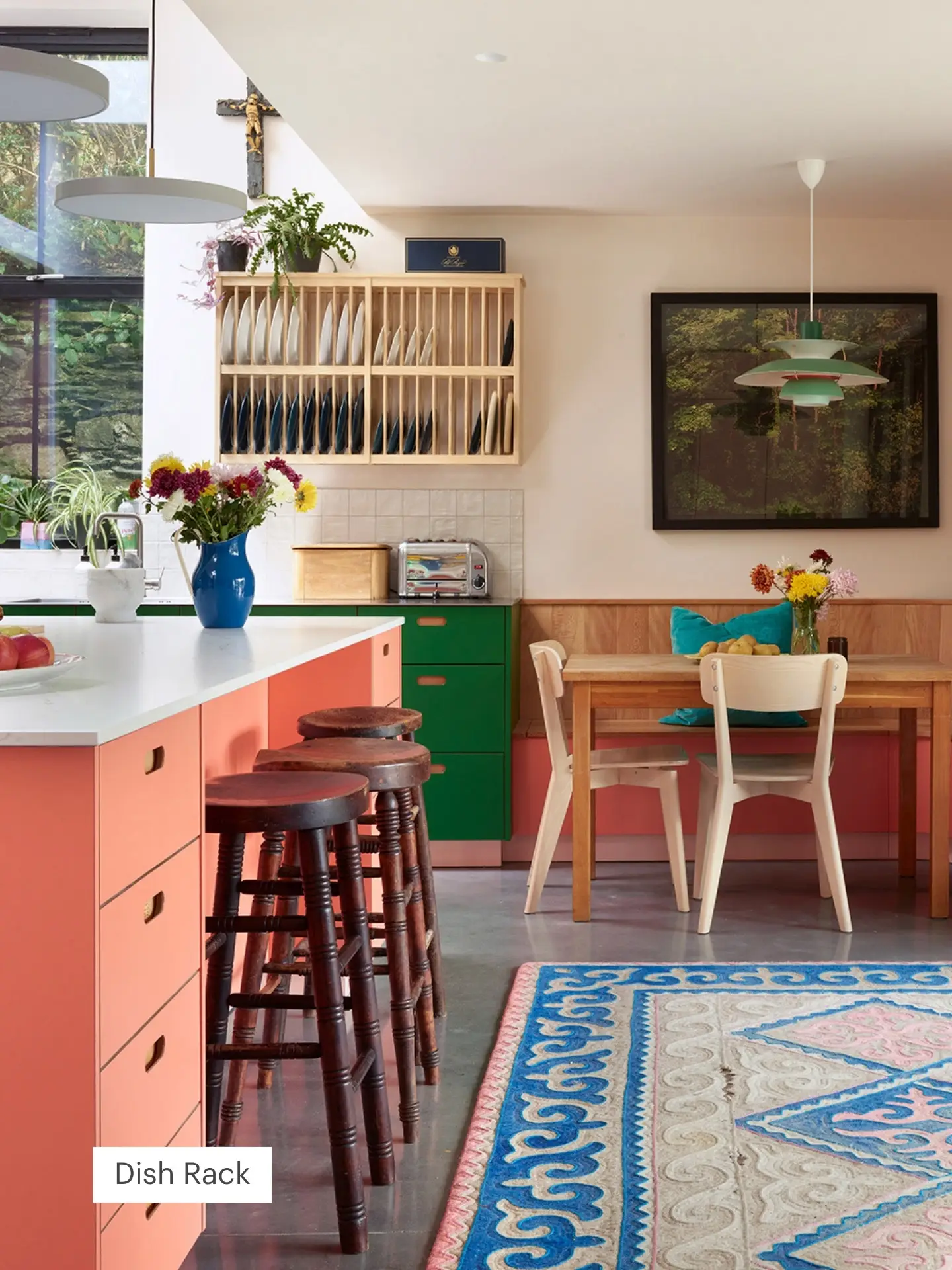 Wooden dish rack fixed to the wall in a colourful pluck kitchen.