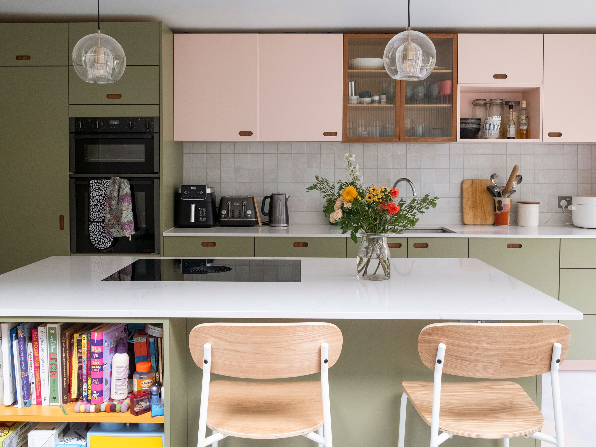 Pluck's pink, green and mustard yellow cupboards in an open plan kitchen with an island.
