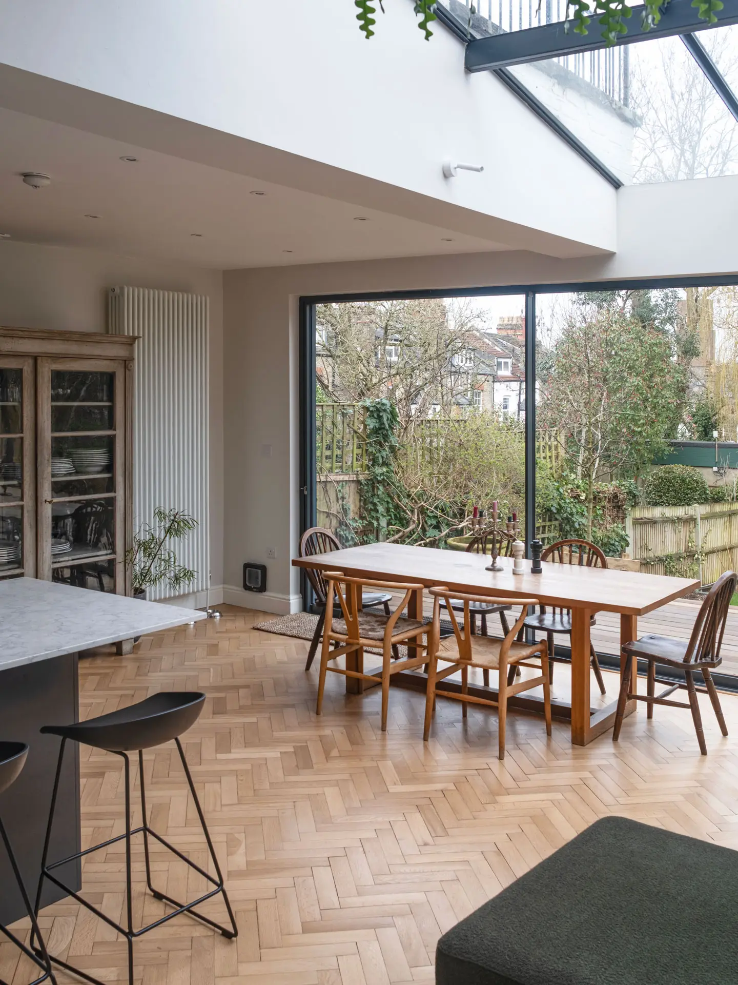 Cool hues in an open plan Pluck kitchen including a larder, shelving and glass cabinet.