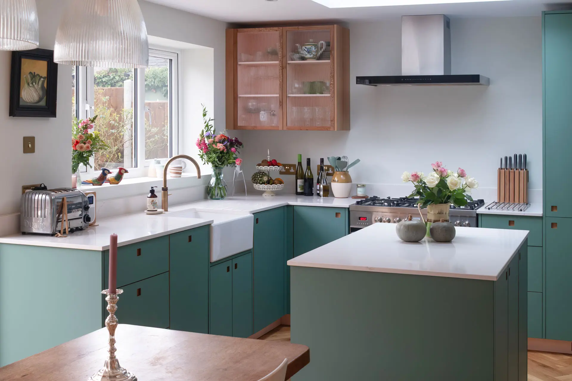 A kitchen in Greenwich, London, with Blue Green cabinetry by Pluck, white worktops, parquet flooring and art from around the world.