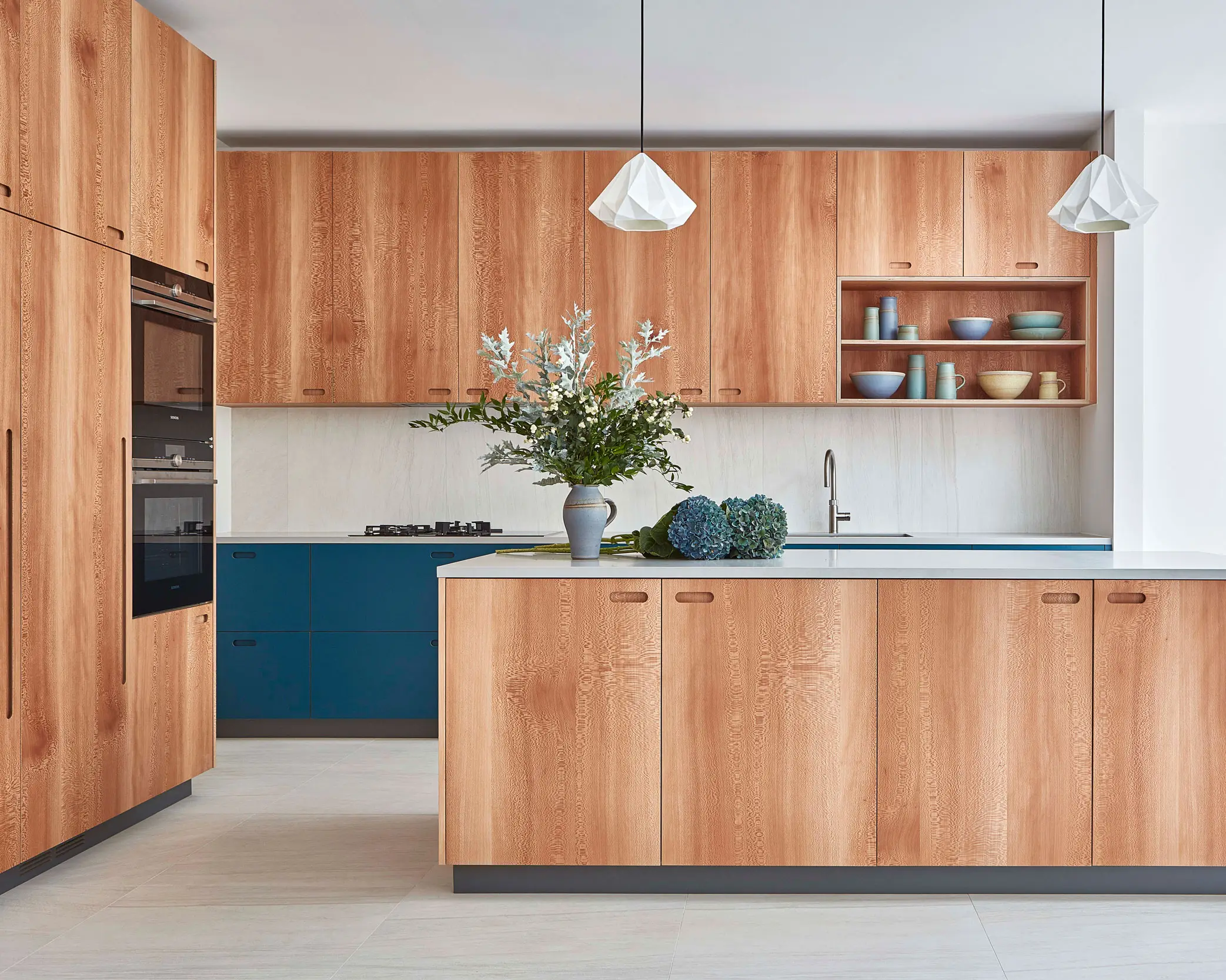 Large kitchen with london plane wood cabinetry and grey worktops.