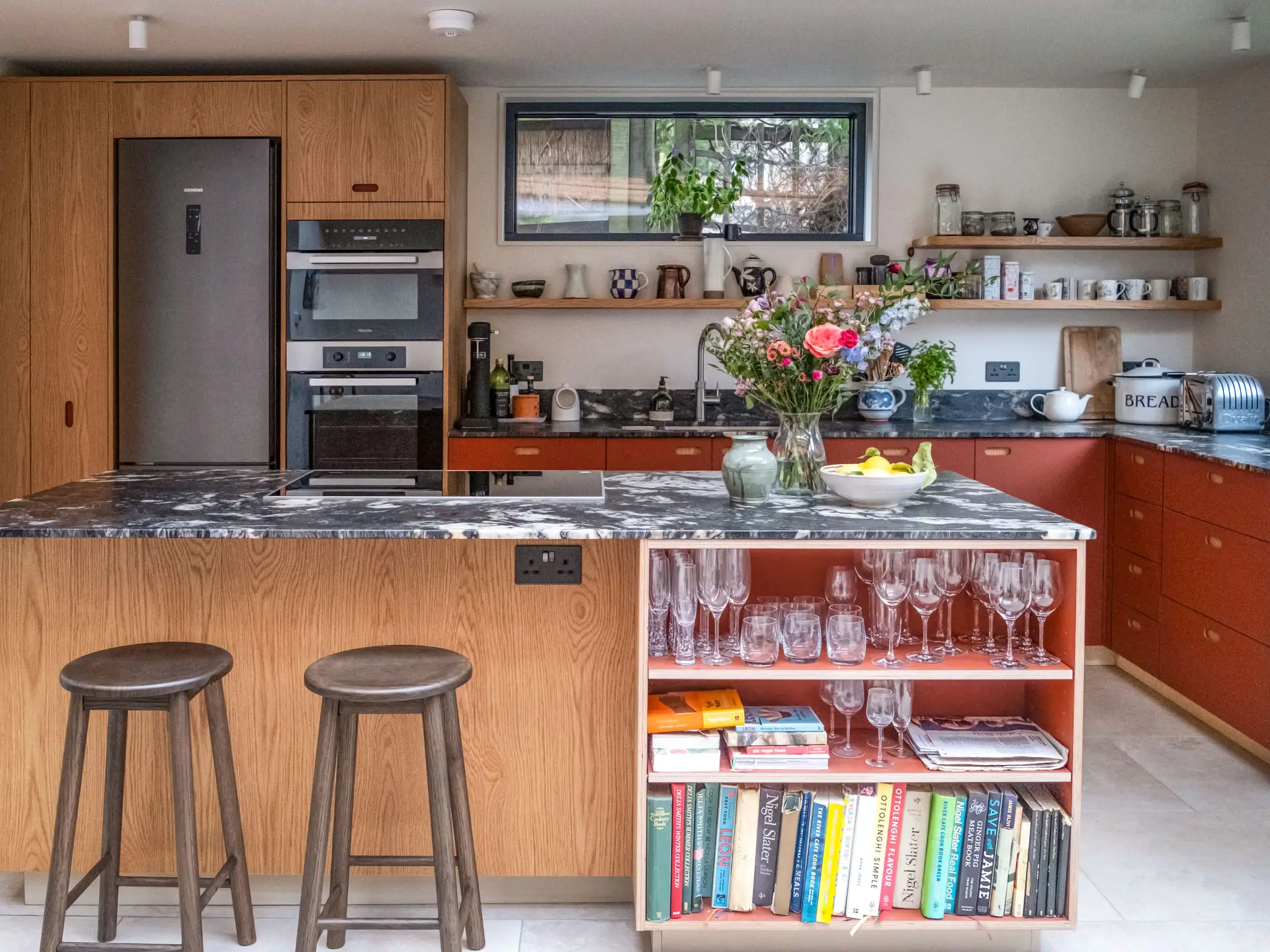 A Pluck kitchen in Kentish Town with oak and terracotta cabinetry including an island and shelving.