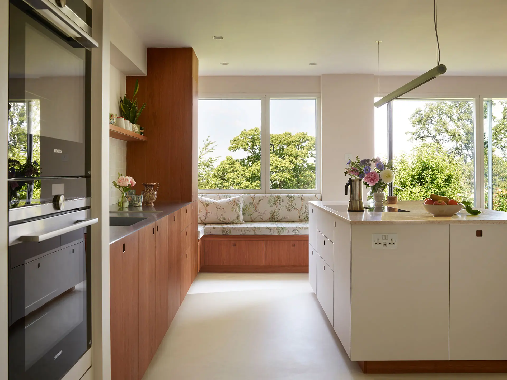 A Pluck kitchen in London with white and cherry wood custom cabinetry and a soft pink utility.