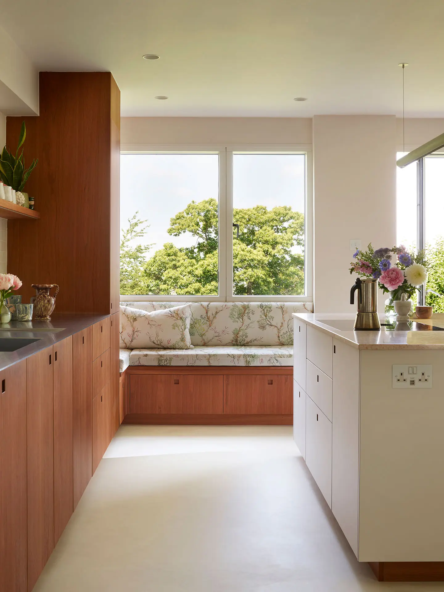 A Pluck kitchen in London with white and cherry wood custom cabinetry and a soft pink utility.