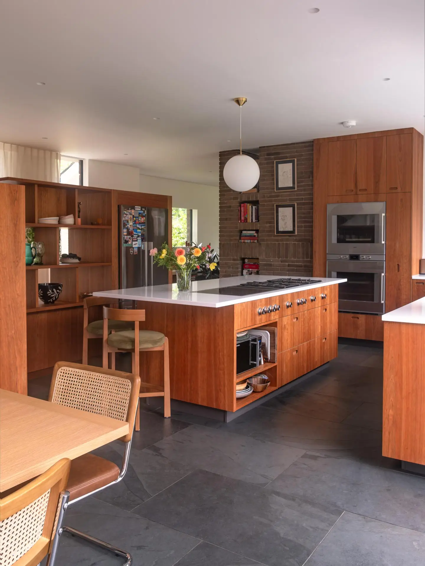 A Pluck kitchen in London with cherry wood custom cabinetry in an open plan home with an island and cooking kit.